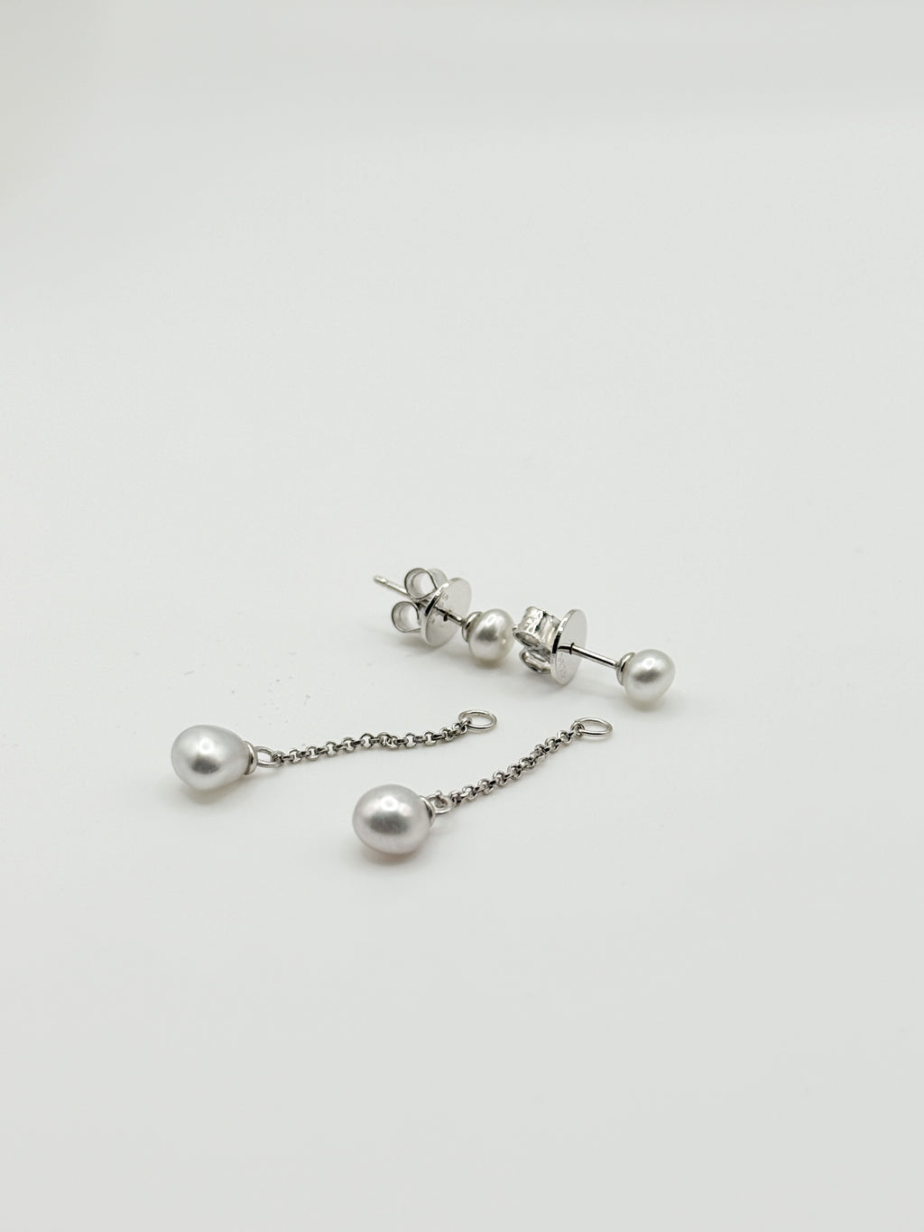 Sterling silver earrings with white South Sea keshi pearls showing both stud and drop chain styles on white background