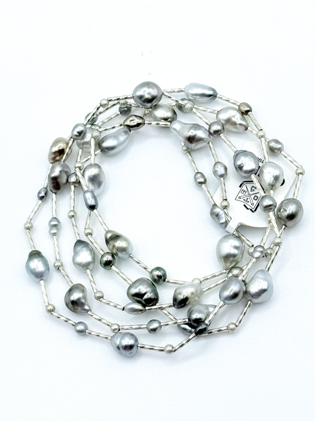 Long sterling silver station necklace with Tahitian keshi pearls coiled in circular formation on white background, showing the full 90cm length 