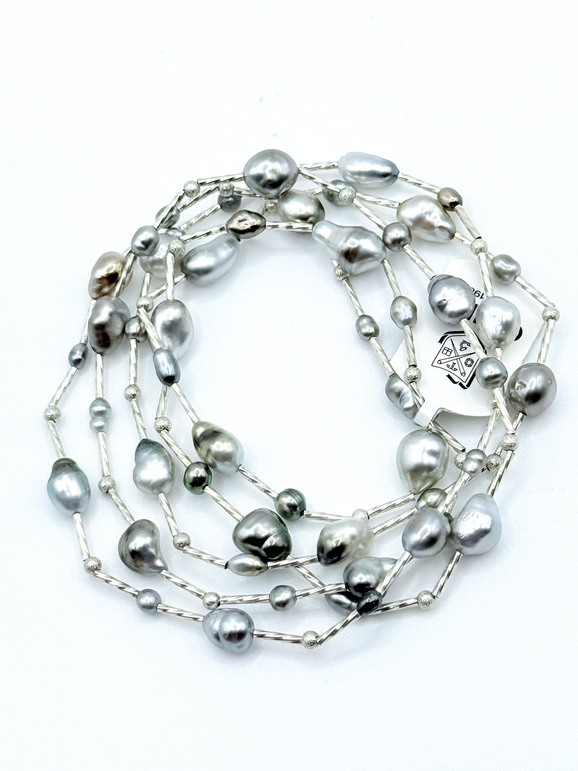 Long sterling silver station necklace with Tahitian keshi pearls coiled in circular formation on white background, showing the full 90cm length 