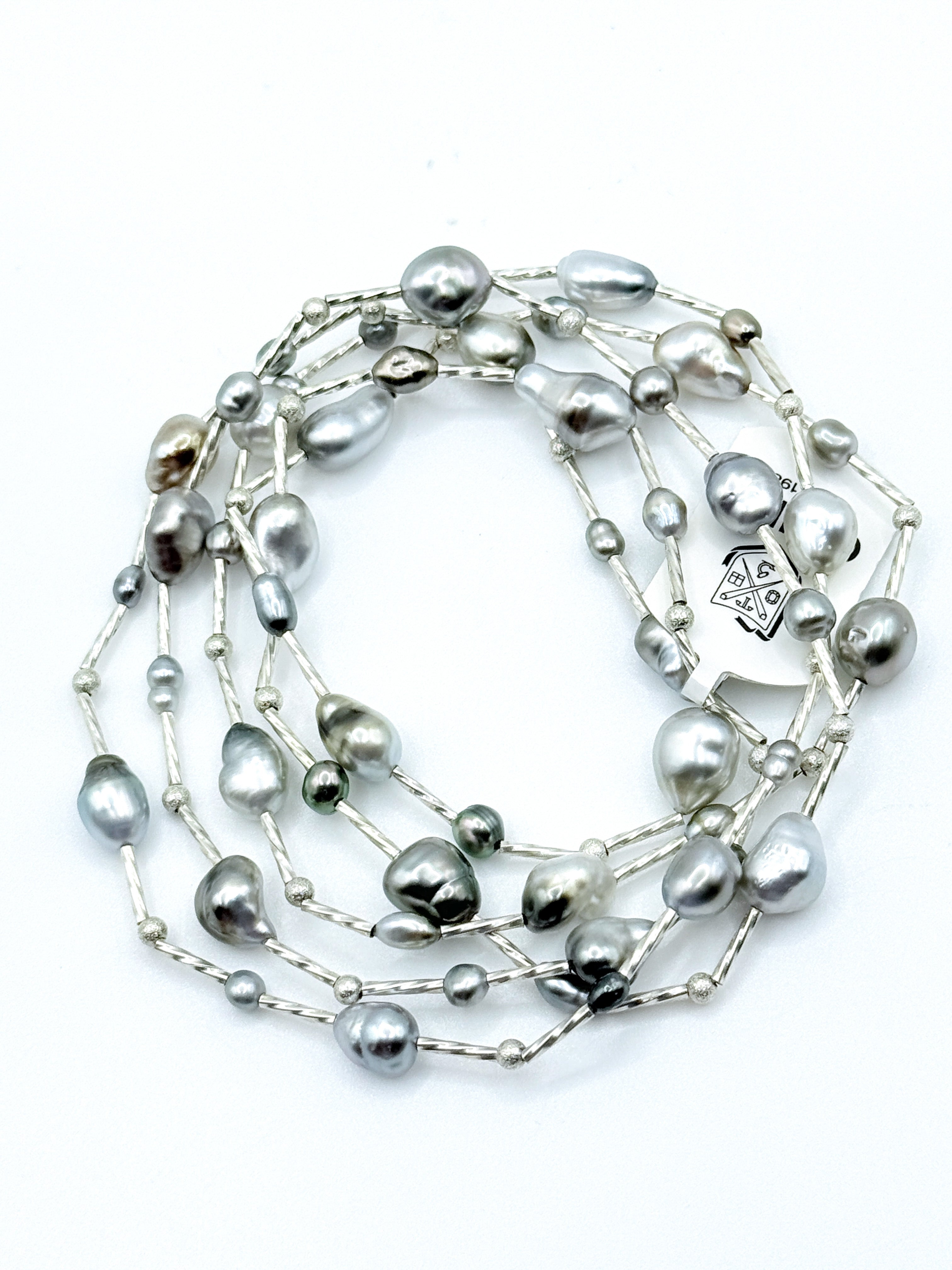 Long sterling silver station necklace with Tahitian keshi pearls coiled in circular formation on white background, showing the full 90cm length 