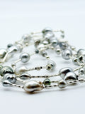 Artistic close-up of sterling silver station necklace with Tahitian keshi pearls in soft focus, highlighting the lustrous surfaces and organic baroque shapes of the pearls