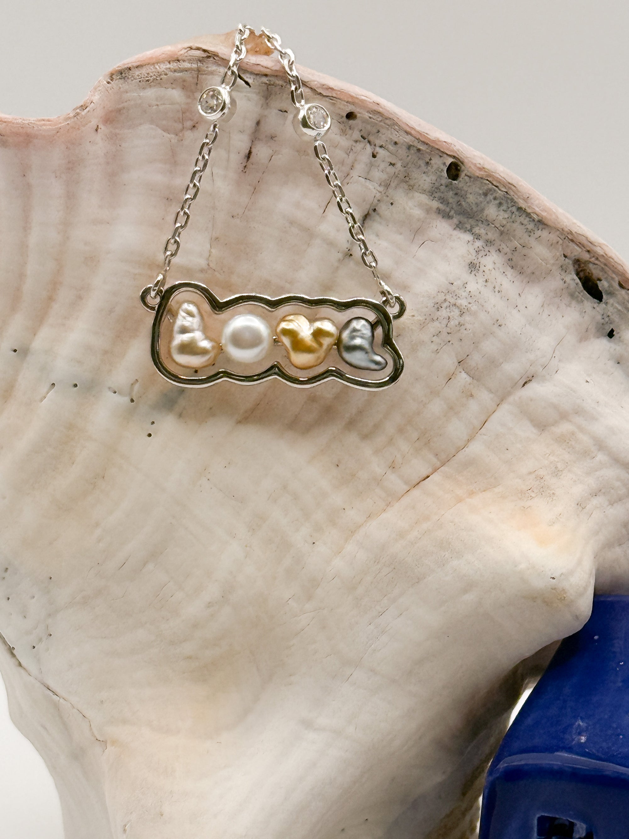 Close-up detail of sterling silver 'LOVE' pendant necklace with mixed South Sea and Tahitian keshi pearls on white background, highlighting the variety of pearl colours and CZ chain stations