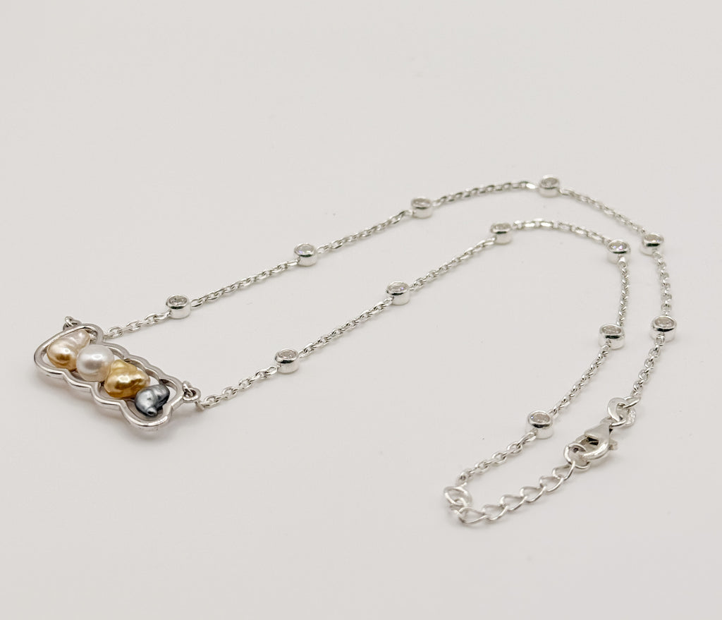 Sterling silver 'LOVE' pendant necklace with mixed keshi pearls arranged in flowing curve on white background, showing the full chain length with crystal stations and adjustable clasp