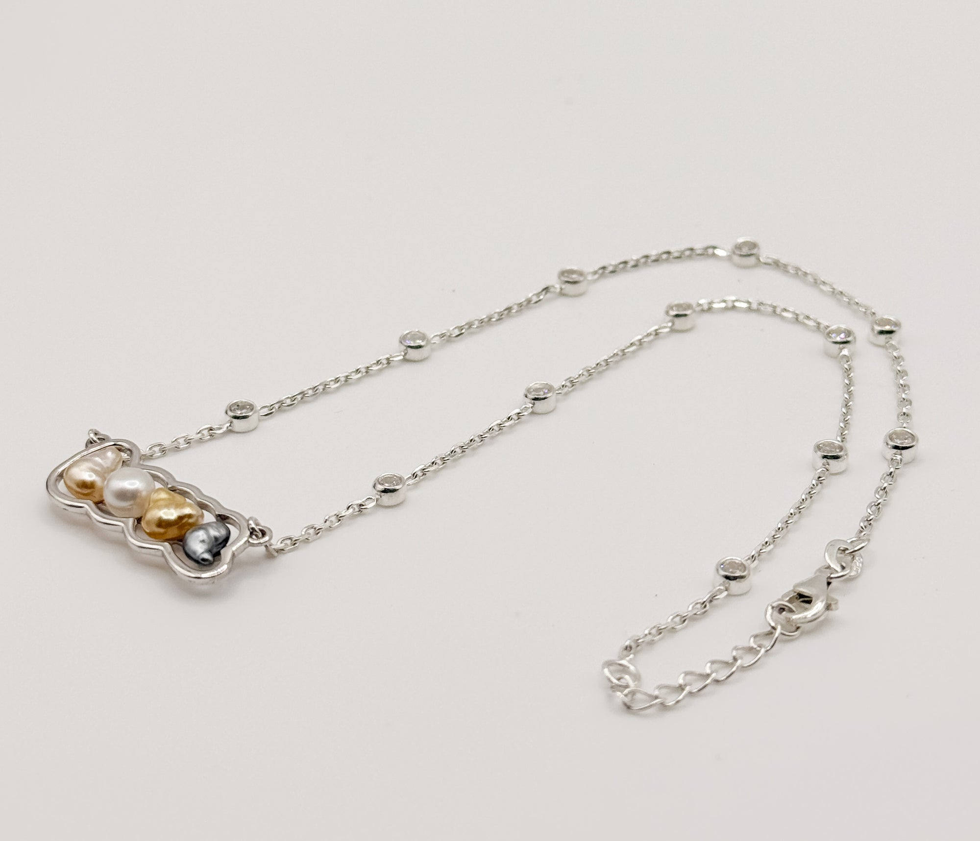 Sterling silver 'LOVE' pendant necklace with mixed keshi pearls arranged in flowing curve on white background, showing the full chain length with crystal stations and adjustable clasp