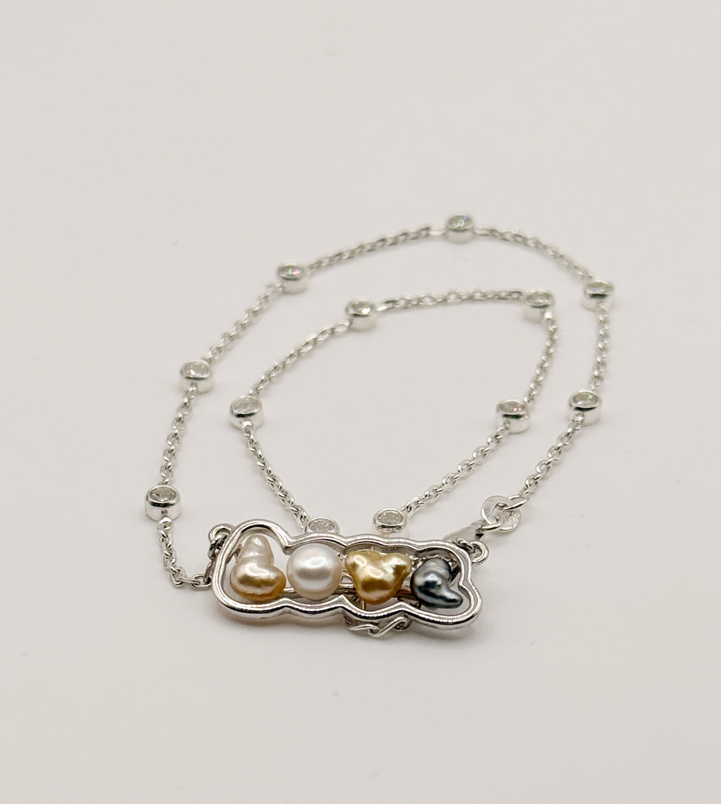 Sterling silver 'LOVE' pendant necklace with mixed keshi pearls laid flat on white background, showing the crystal-studded chain and multi-coloured pearl arrangement front view