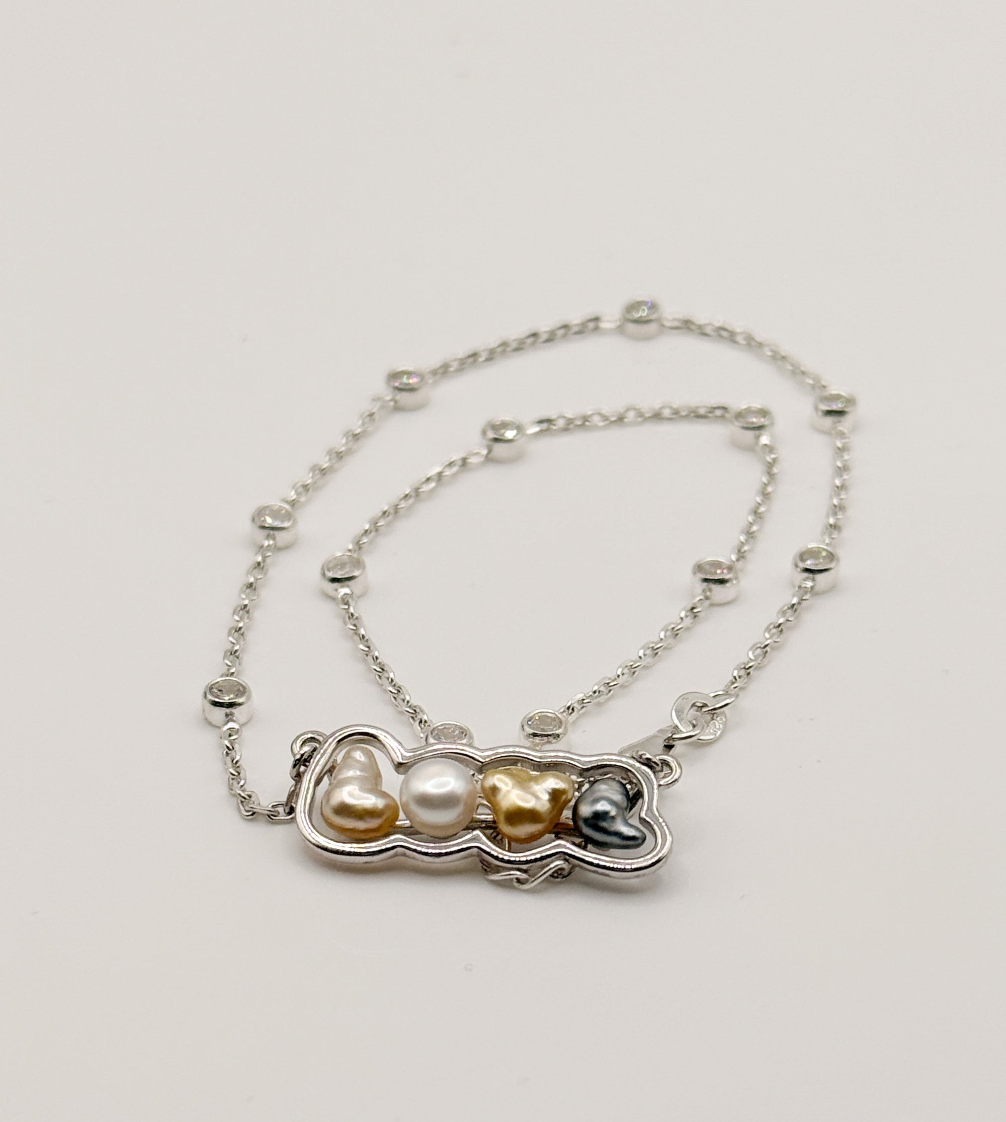 Sterling silver 'LOVE' pendant necklace with mixed keshi pearls laid flat on white background, showing the crystal-studded chain and multi-coloured pearl arrangement front view