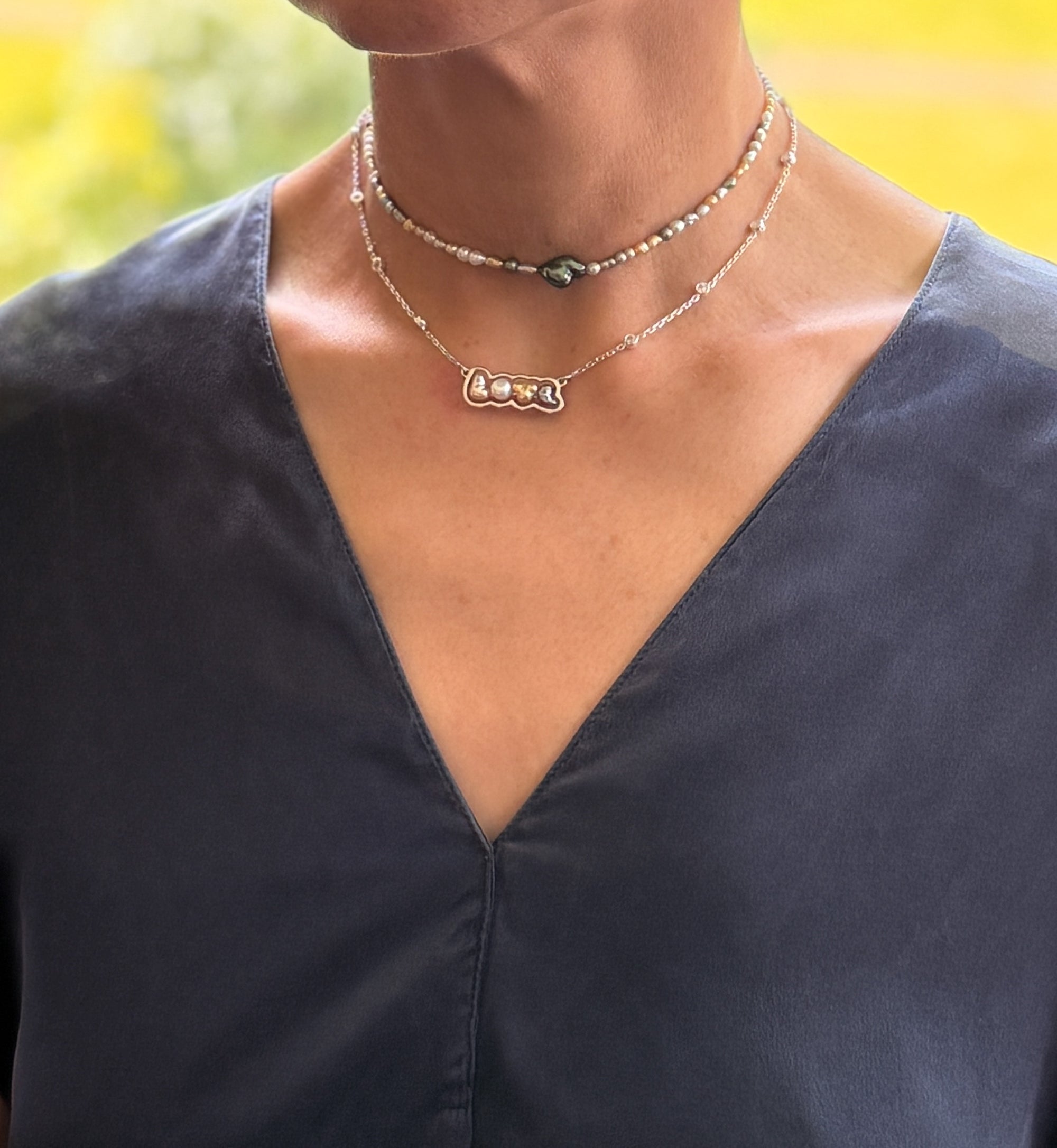 Sterling silver 'LOVE' pendant necklace with mixed keshi pearls laid flat on white background, showing the crystal-studded chain and multi-coloured pearl arrangement