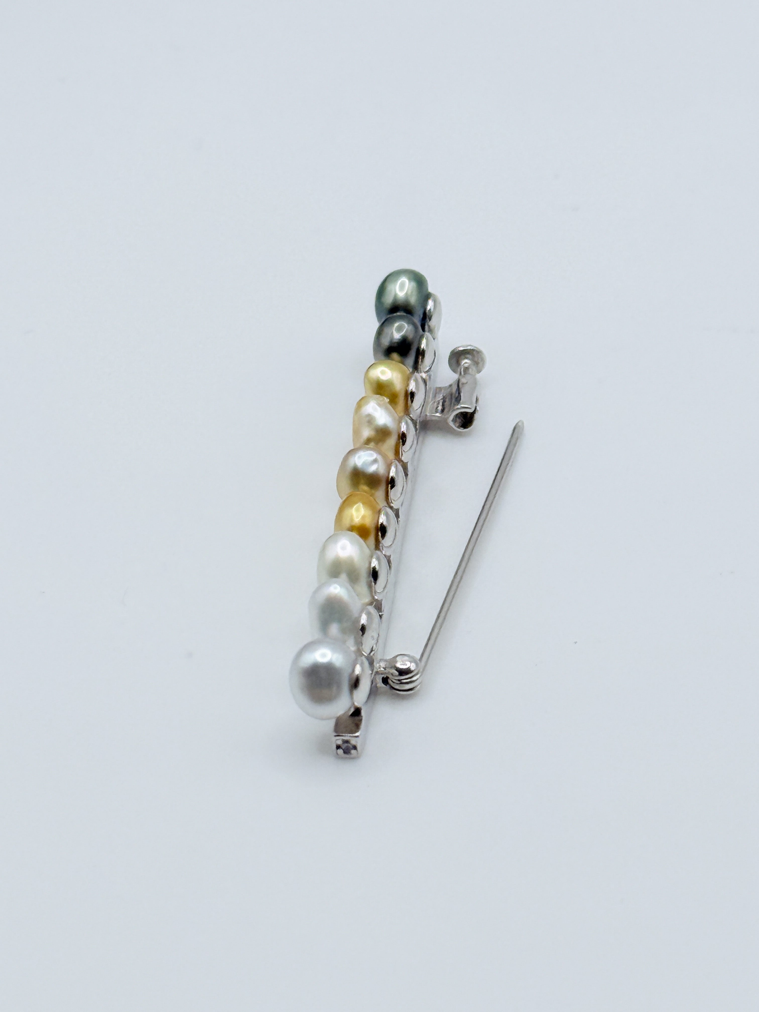 Close-up detail of sterling silver bar pin brooch with heart-shaped keshi pearls on white background, highlighting the pin mechanism and mixed pearl colours including Tahitian and South Sea varieties