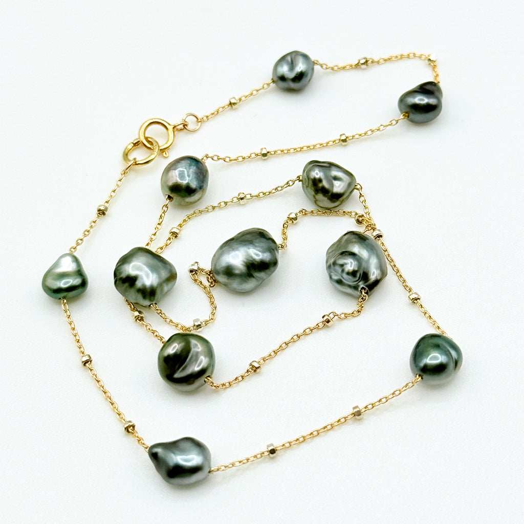 Tahitian Keshi pearl station necklace full lay flat on white background showing 14K gold filled chain blue overtone baroque pearls