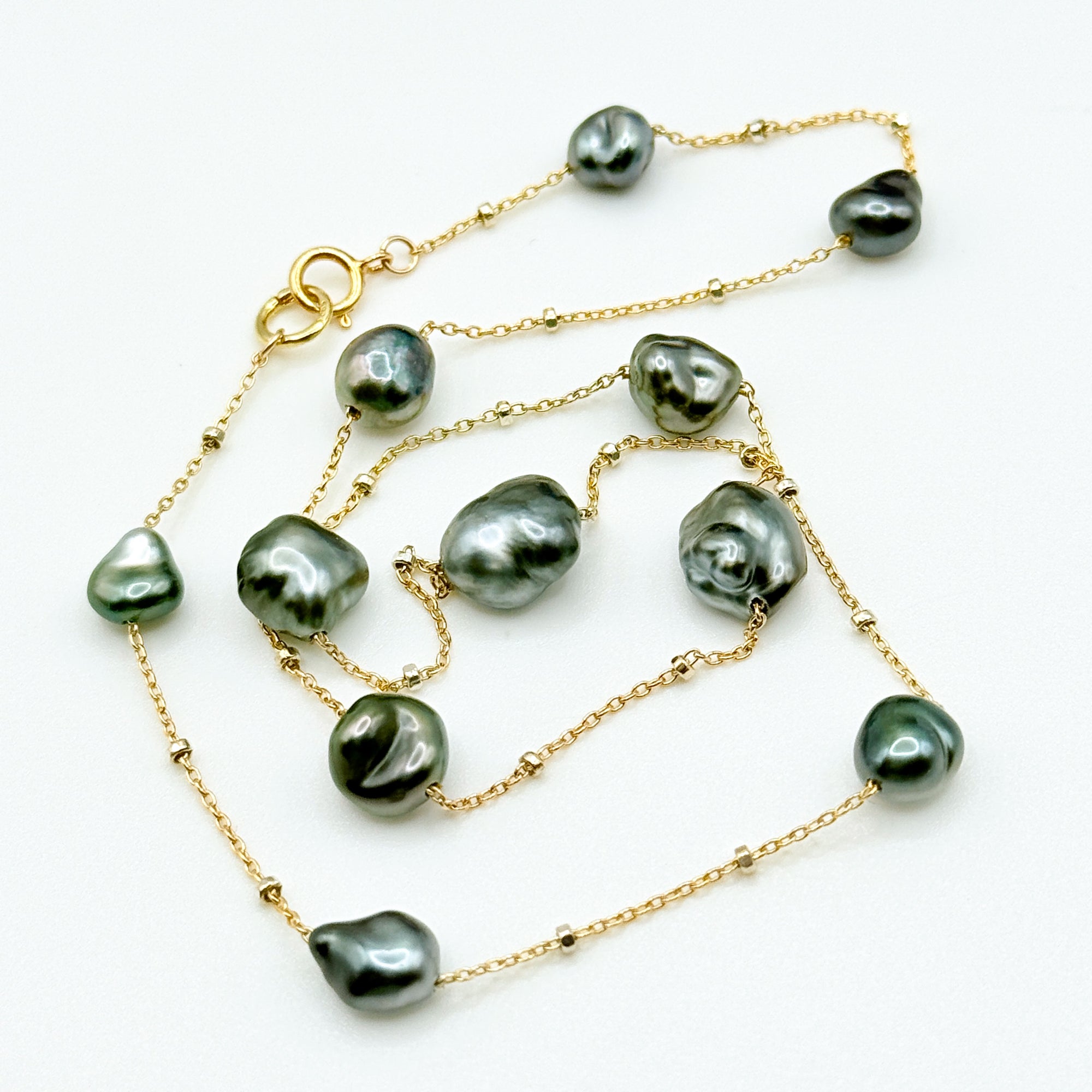 Tahitian Keshi pearl station necklace full lay flat on white background showing 14K gold filled chain blue overtone baroque pearls