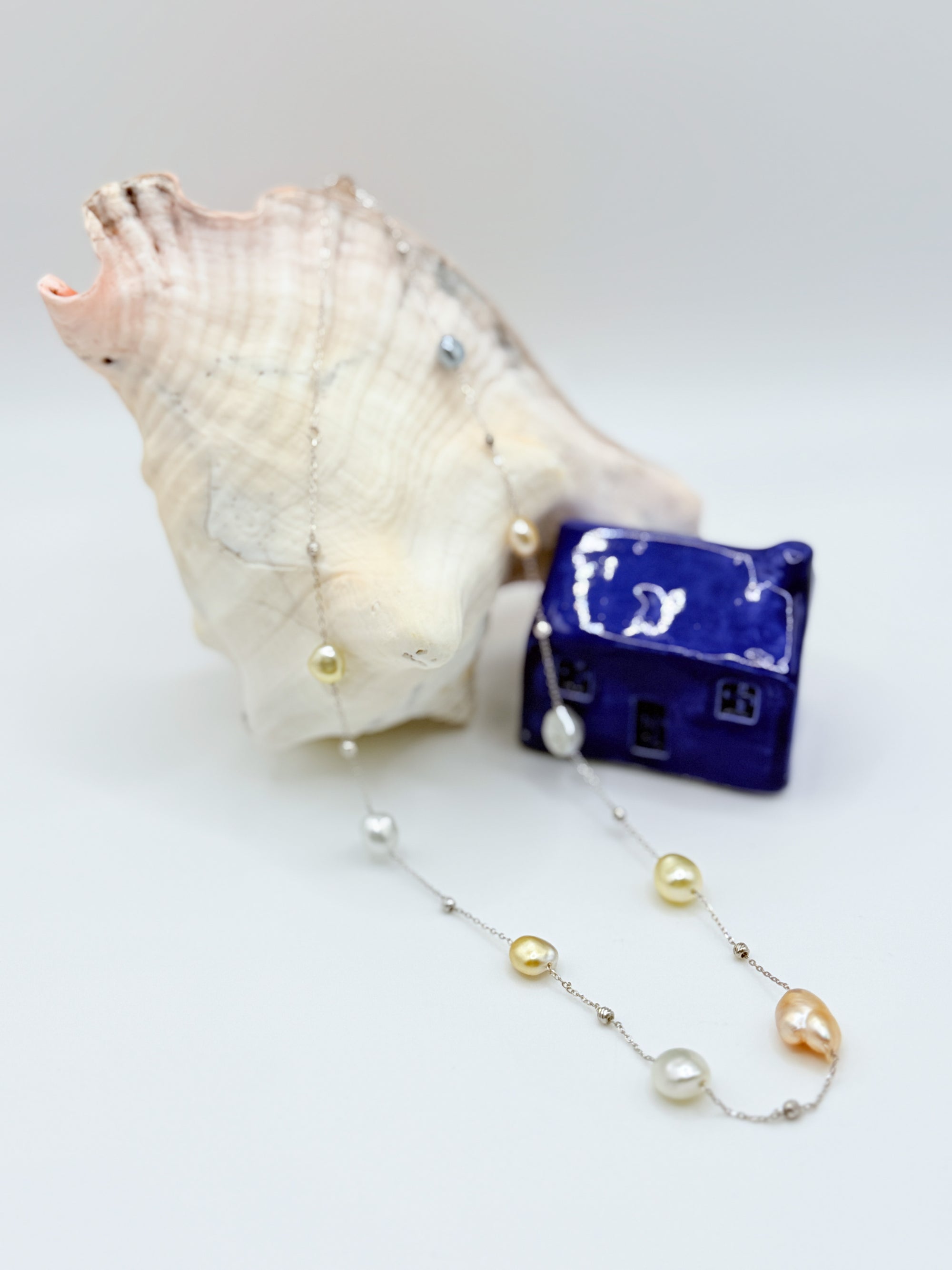South Sea Keshi pearl station necklace detail showing baroque pearls 925 sterling silver chain draped over a sea shell 