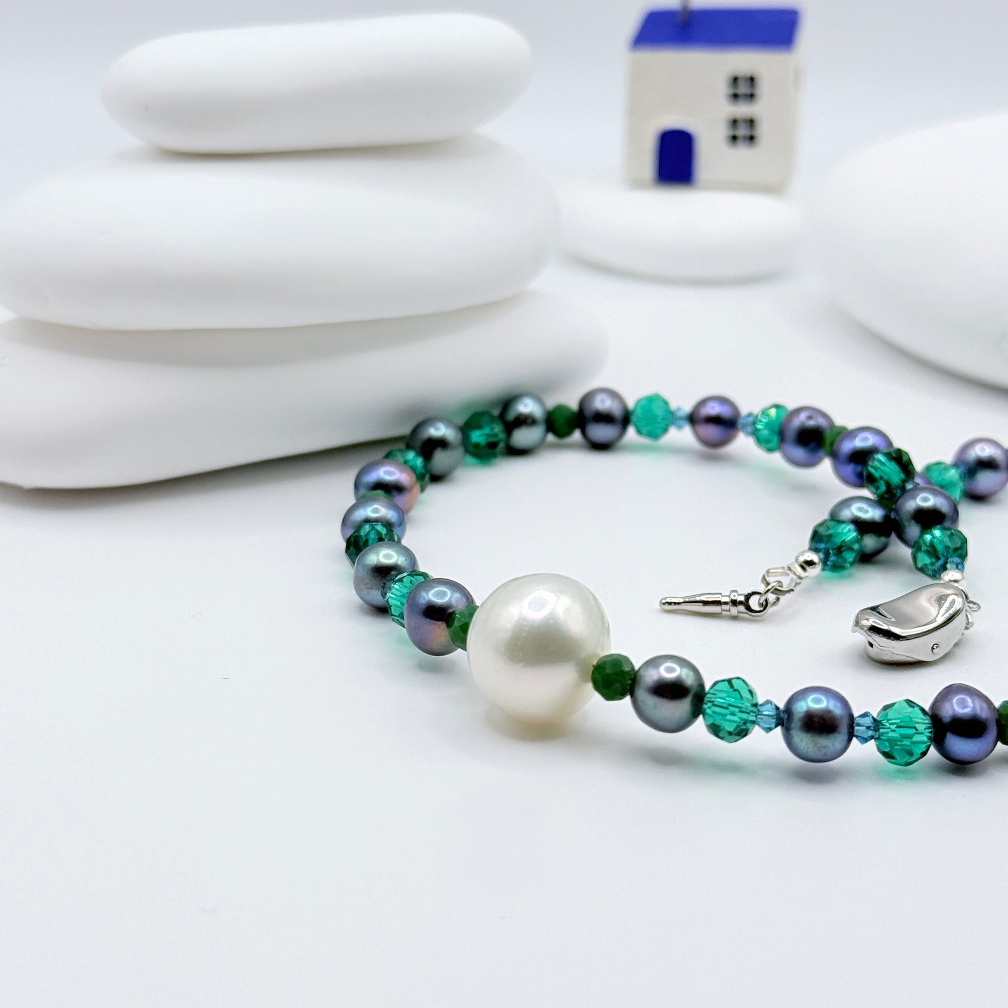 Close up of large white South Sea Baroque pearl surrounded by blue iridescent pearls