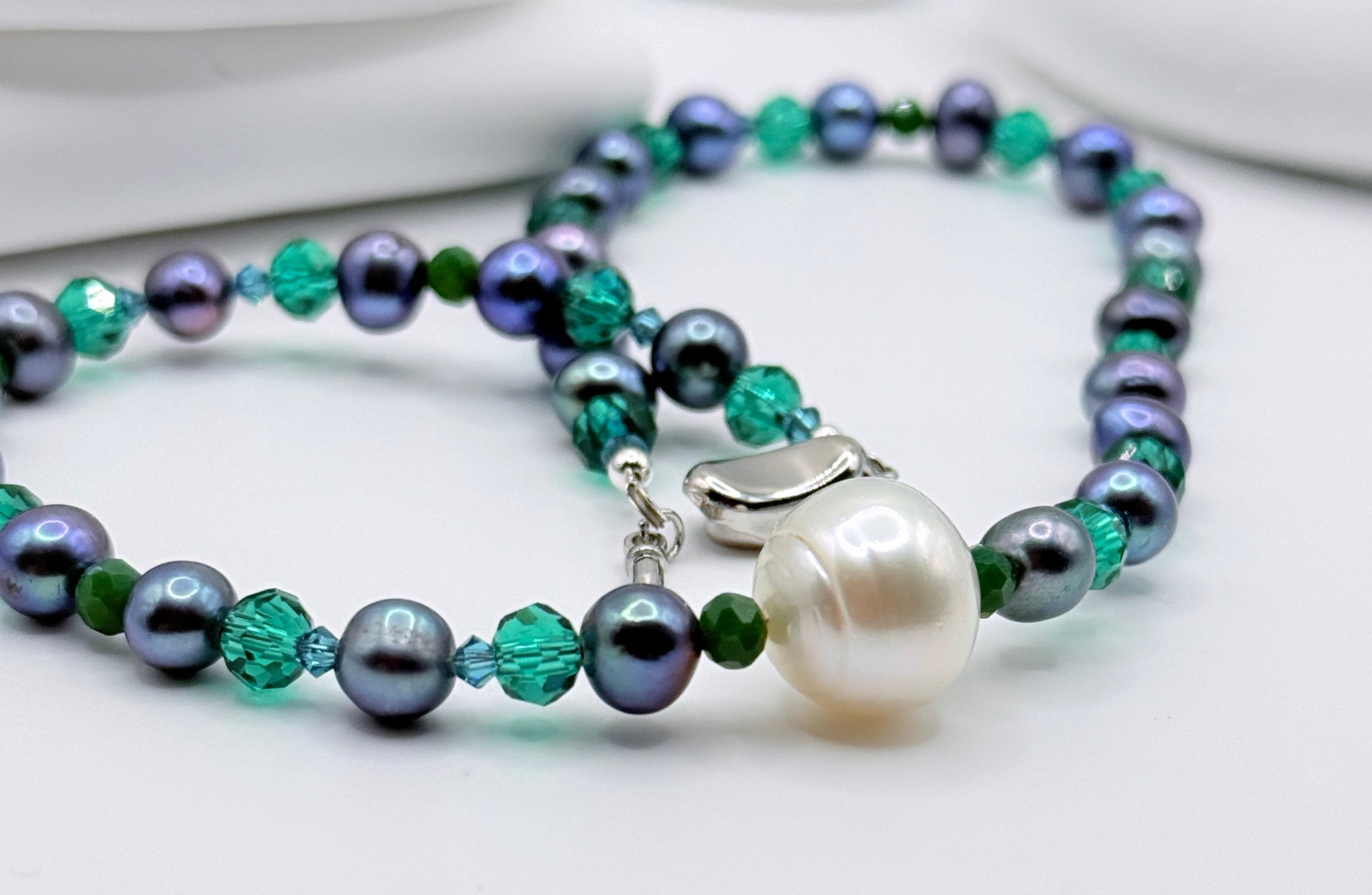 Macro close-up of white south sea baroque pearl and blue-dyed coloured freshwater beaded necklace on a white background