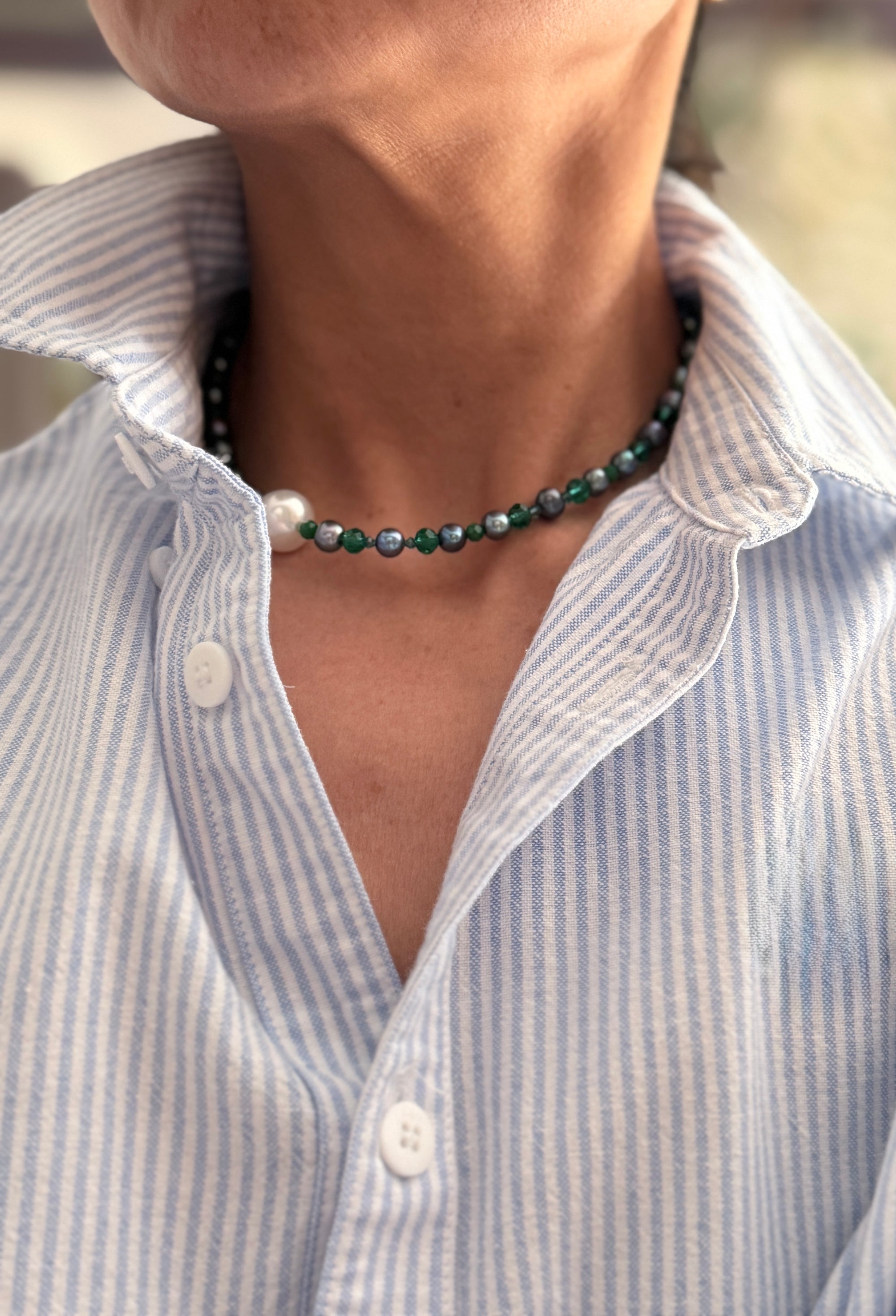 Close-up of a person wearing a blue and white striped shirt with white south sea pearl necklace.