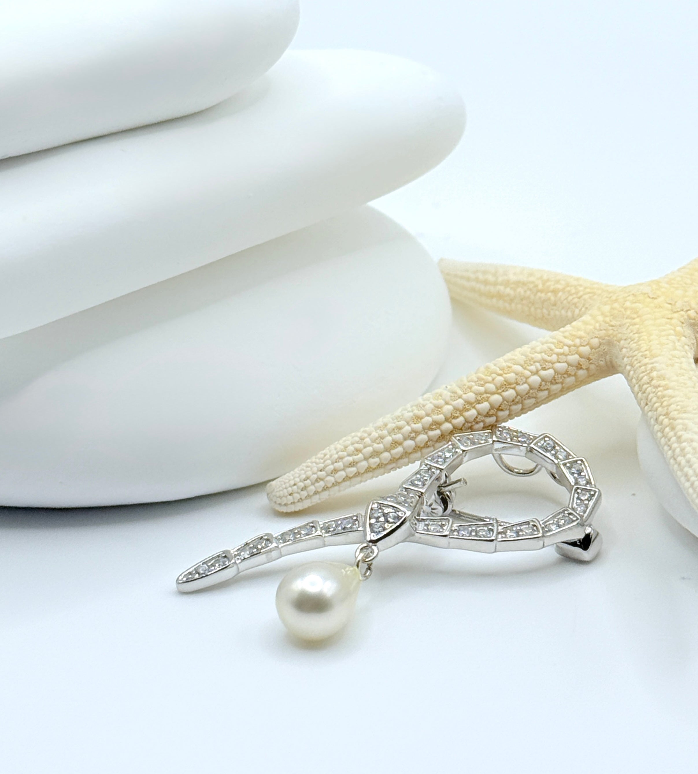 Side view of snake pendant brooch displaying curved design and pearl drop positioning with starfish accent