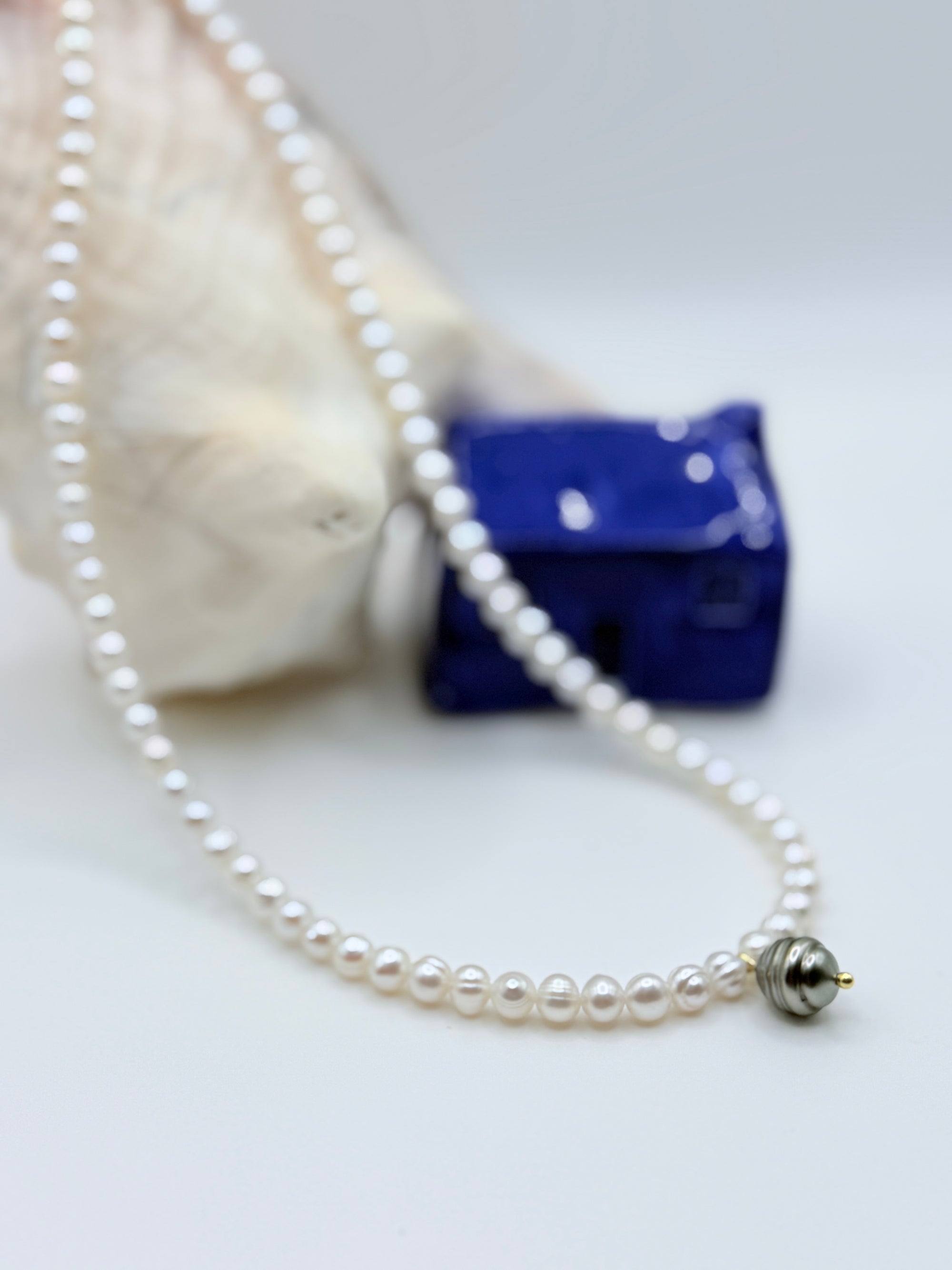 Close-up view of 9mm Tahitian circled pearl charm showing silver green lustre on white freshwater circled pearl strand