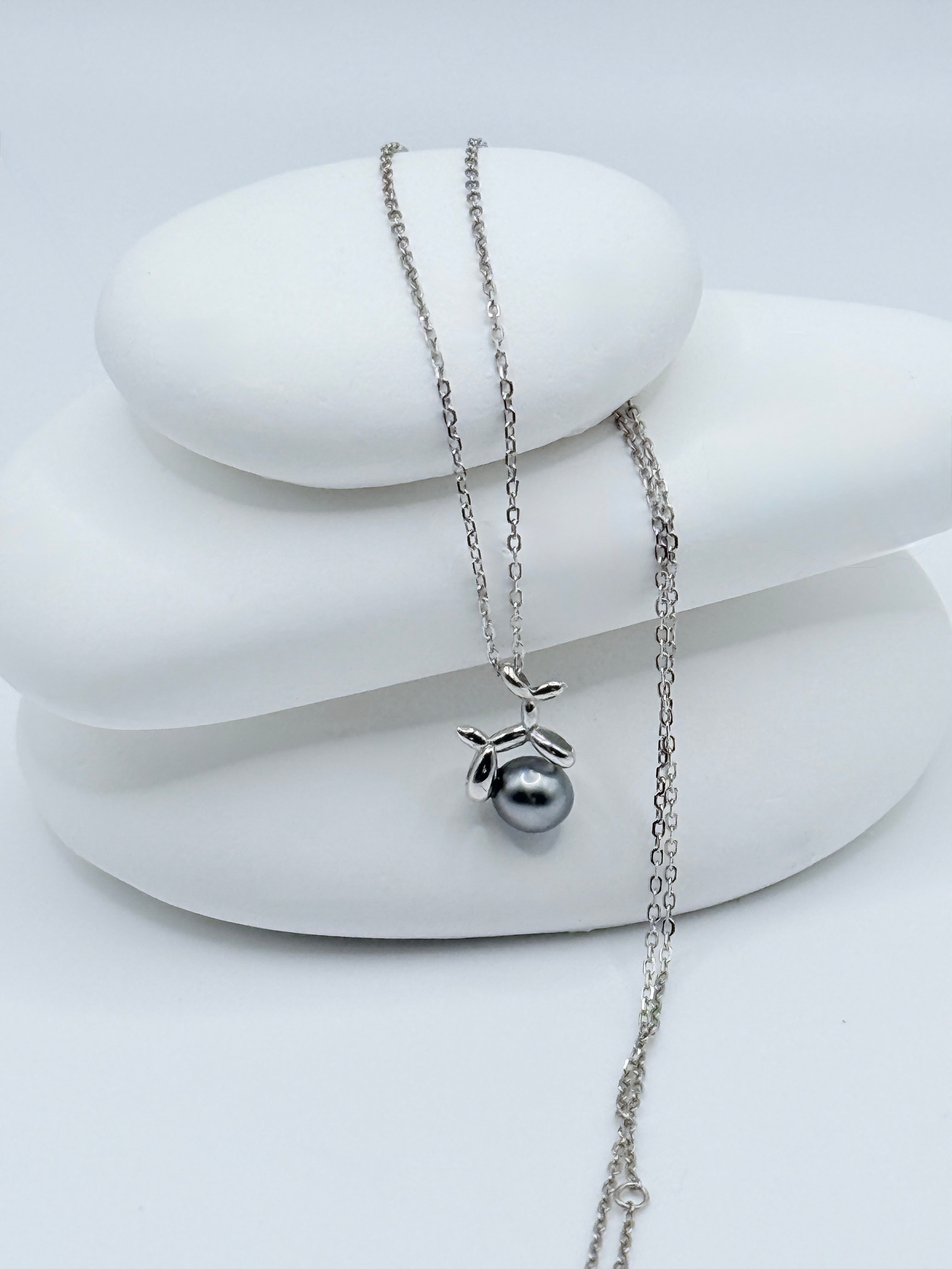 Close-up view of silver balloon dog charm with lustrous Tahitian keshi pearl and sterling silver chain detail