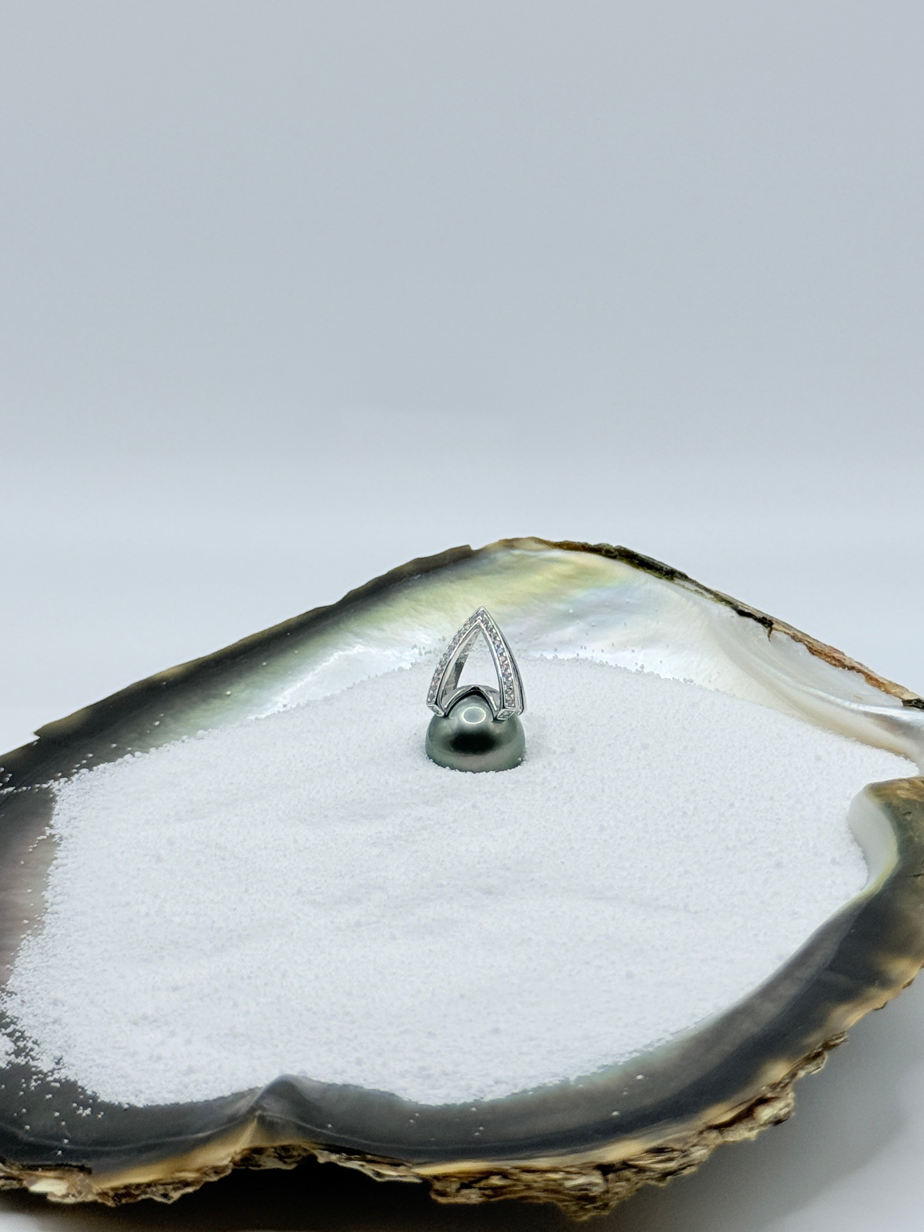 Sterling silver Tahitian pearl pendant displayed in natural oyster shell showing 11-12mm round pearl with green lustre