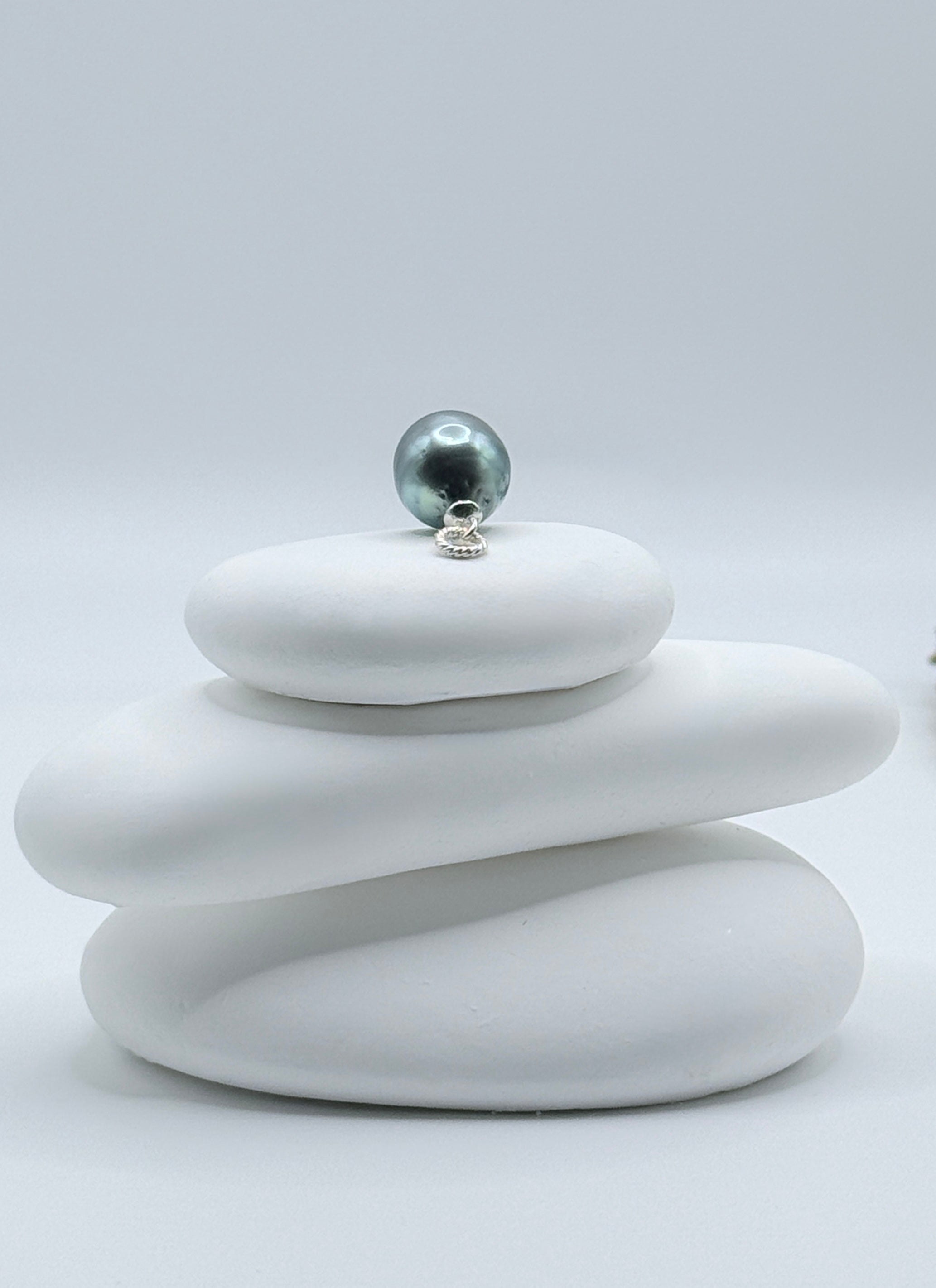 Pear-shaped blue Tahitian baroque pearl pendant with 925 sterling silver bail on white stones showing blue-green reflections