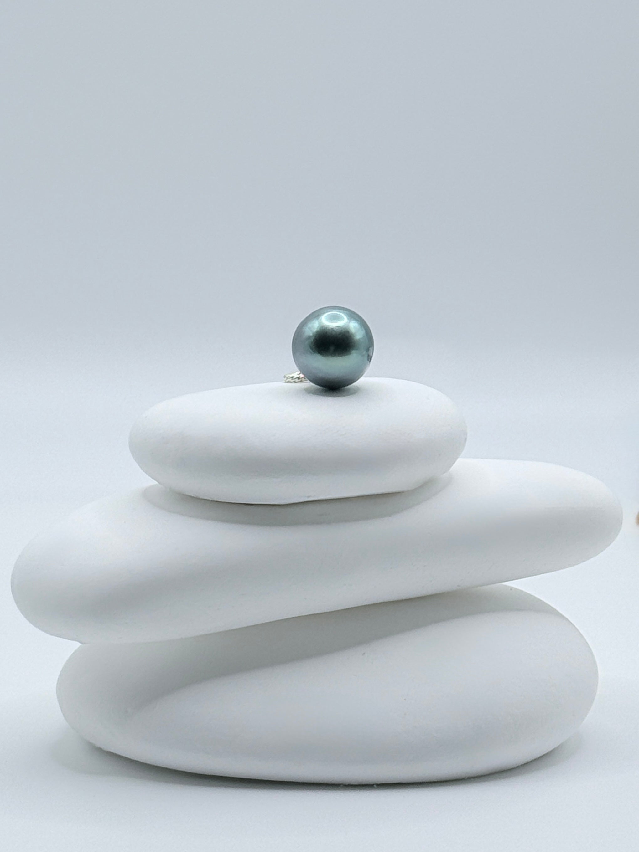 Sterling silver bail blue Tahitian baroque pearl pendant displayed on white stone stack showing pear shape and blue-green colour