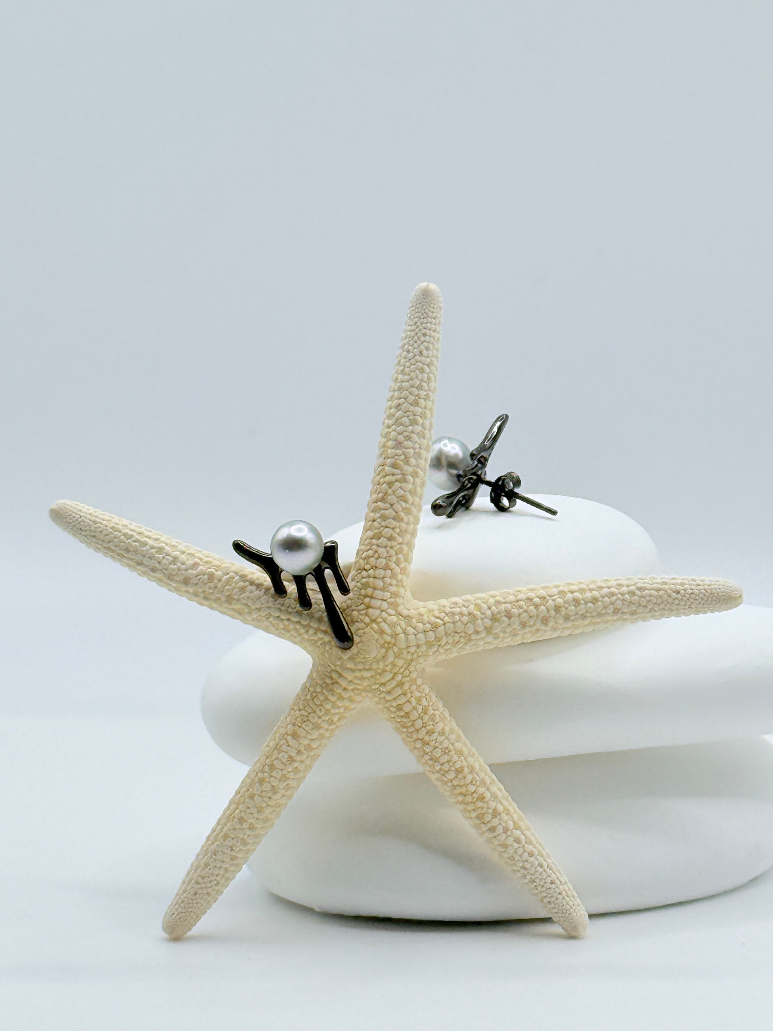 Close-up view of blackened silver melting design earrings with lustrous light blue Akoya pearls on starfish highlighting dramatic contrast