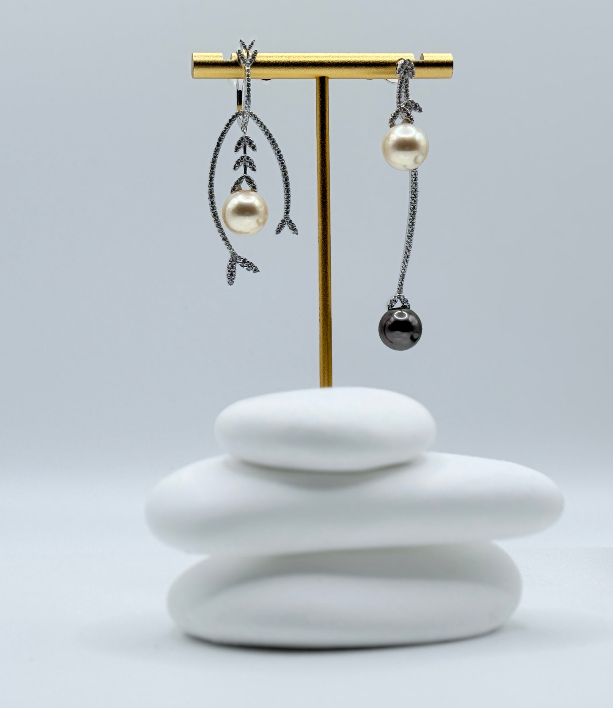 Detailed side view of sterling silver earrings with contrasting botanical and minimalist designs featuring South Sea and Tahitian pearls