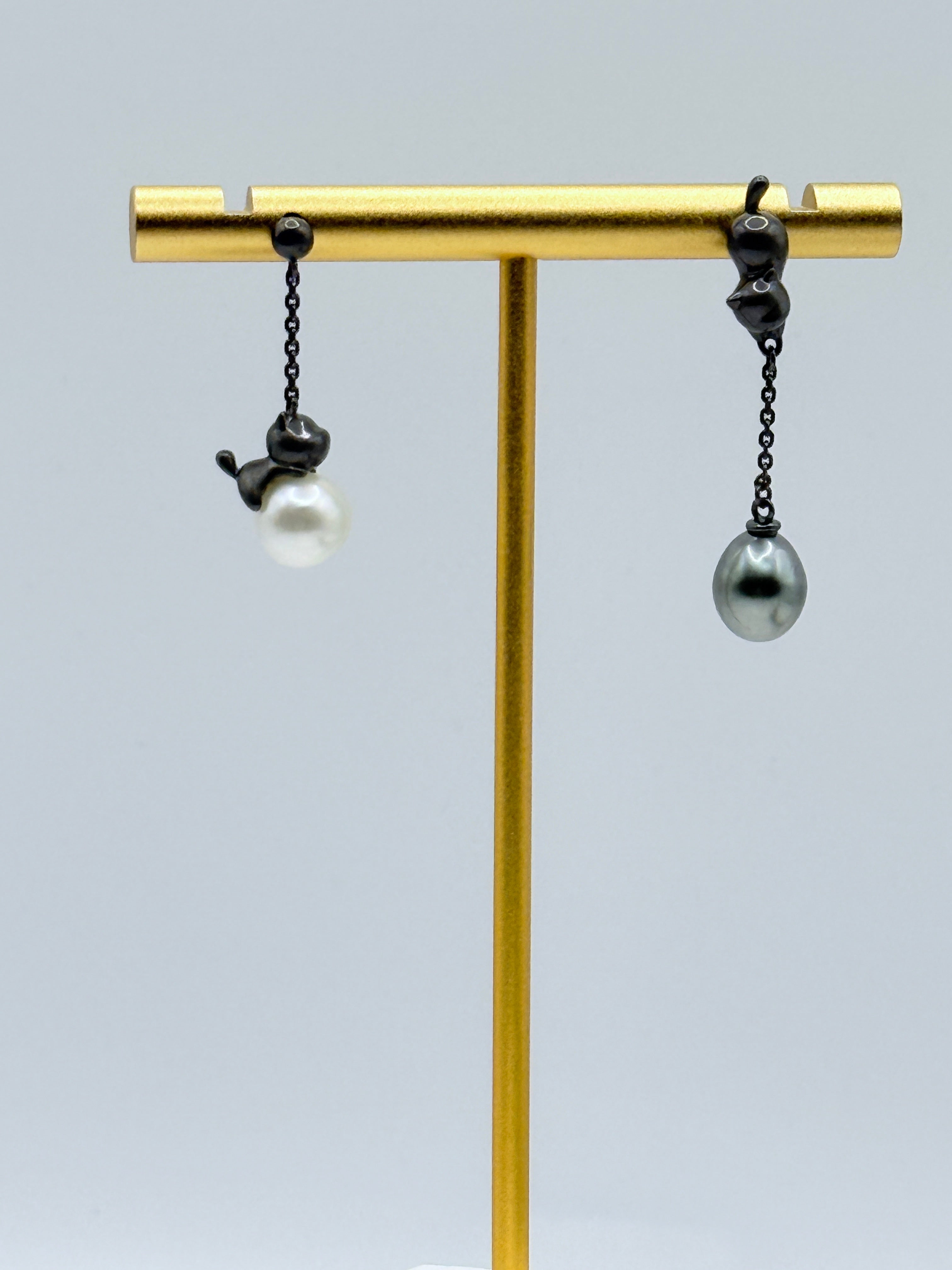 Alternative pairing of cat dangle earrings showing white and dark grey keshi pearls with two different cat designs on gold stand