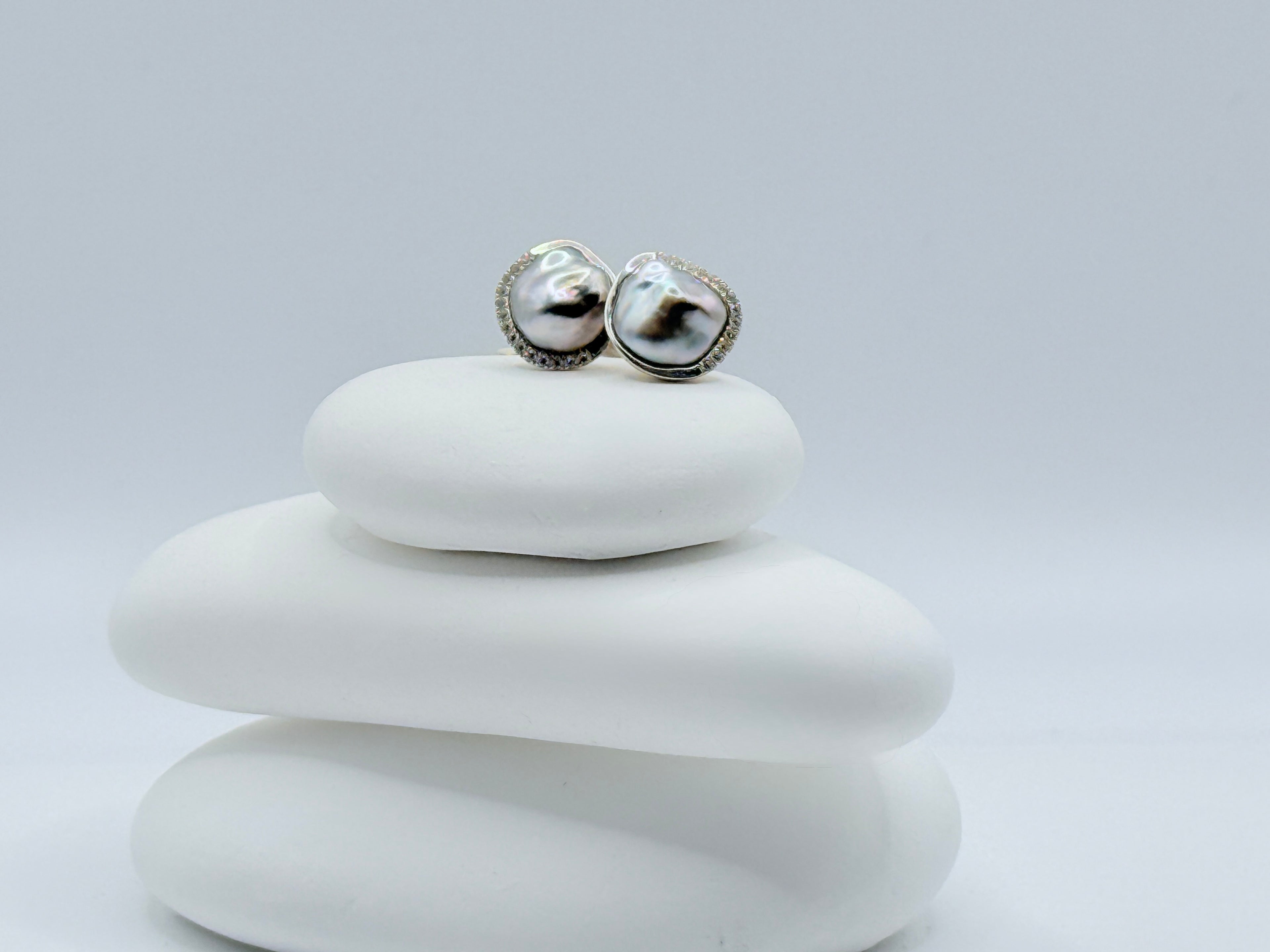 Pair of iridescent Tahitian keshi pearls silver earrings on a white stone showing rainbow colour