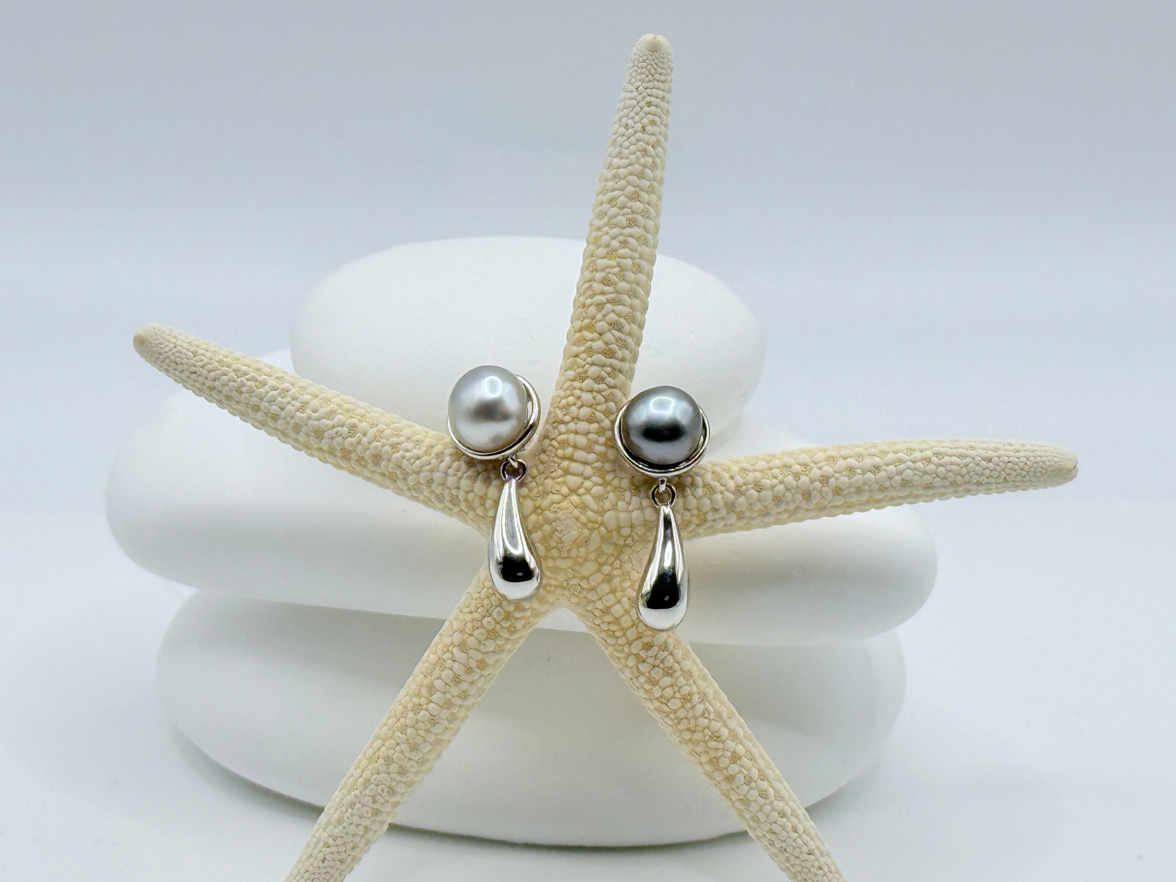 Sterling silver asymmetric earrings with Gambier Island Tahitian keshi pearls and teardrop elements displayed on starfish and white stones
