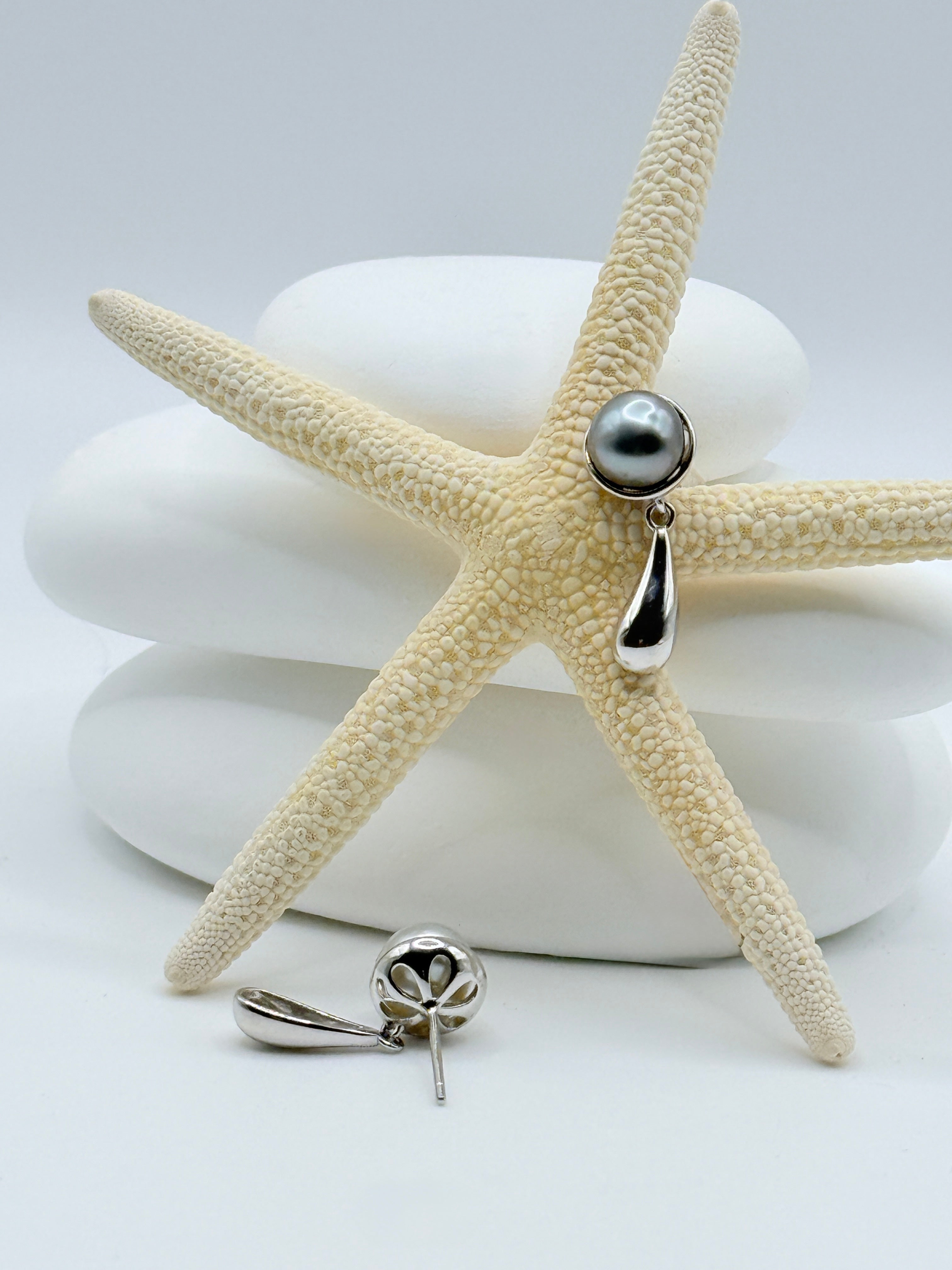 Close-up view of sterling silver teardrop earrings with dark grey Tahitian keshi pearls on starfish showing elegant asymmetric design