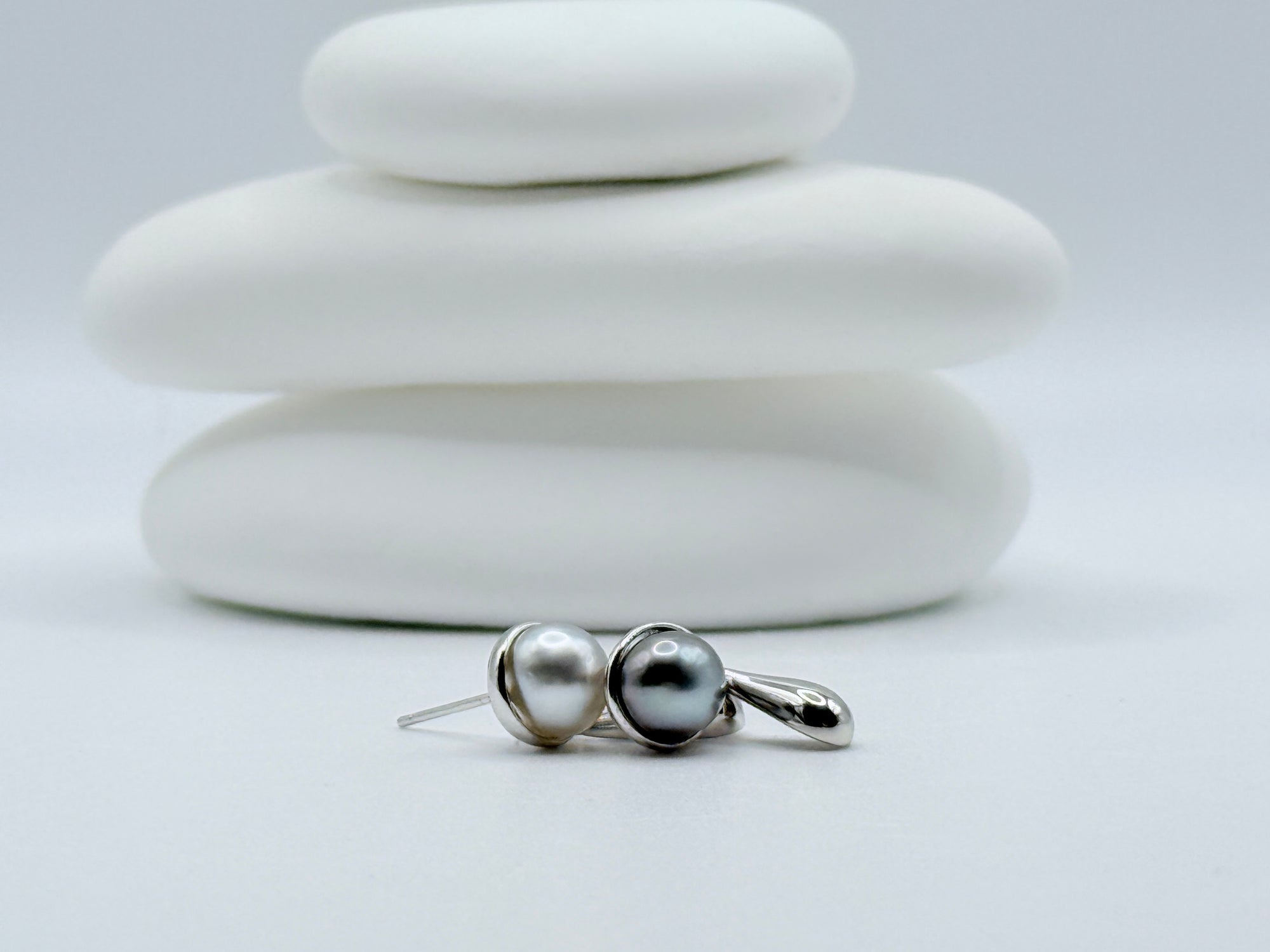 Sterling silver earrings with Gambier Island keshi pearls and polished teardrops displayed on stacked white stones
