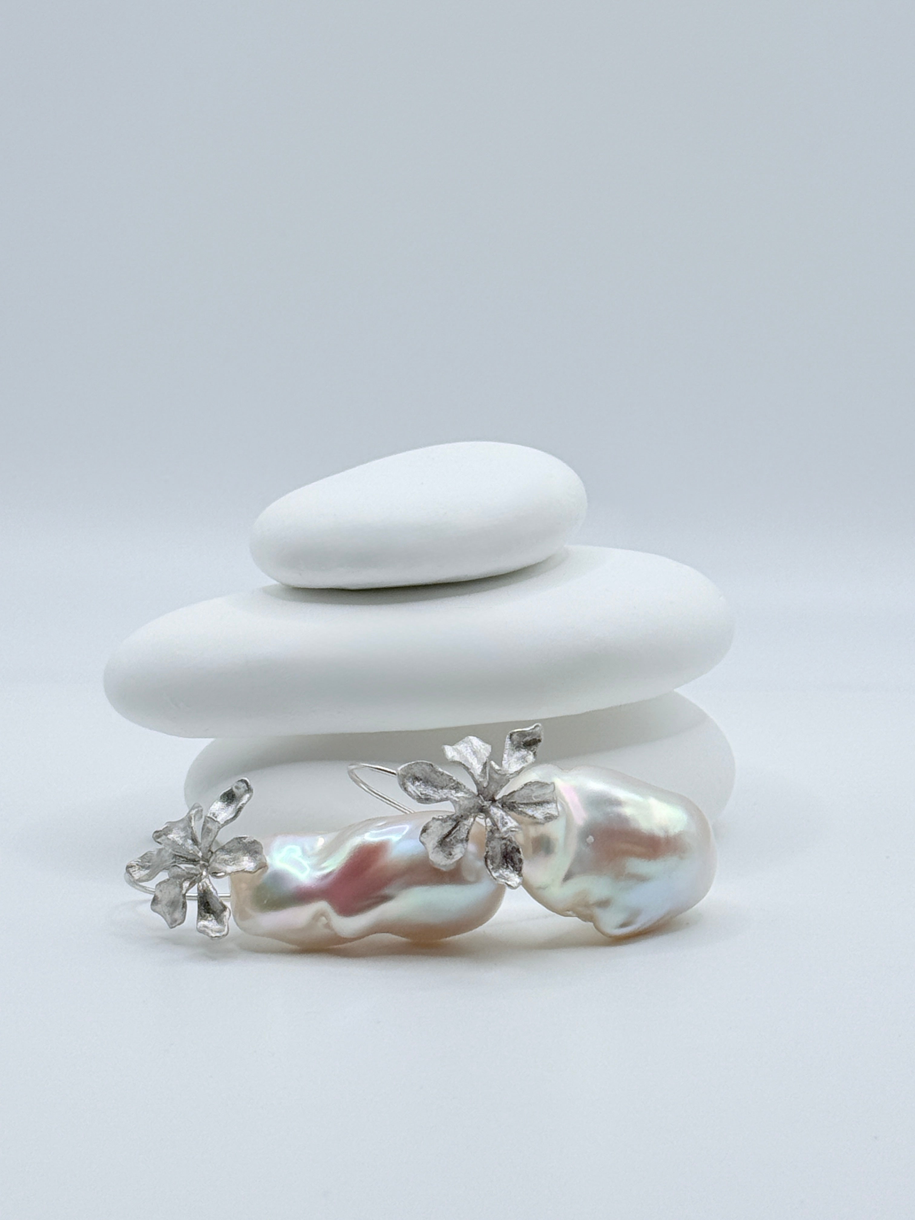 Close-up view of large baroque freshwater pearl earrings showing removable pearl design and sterling silver flower accents on white stones