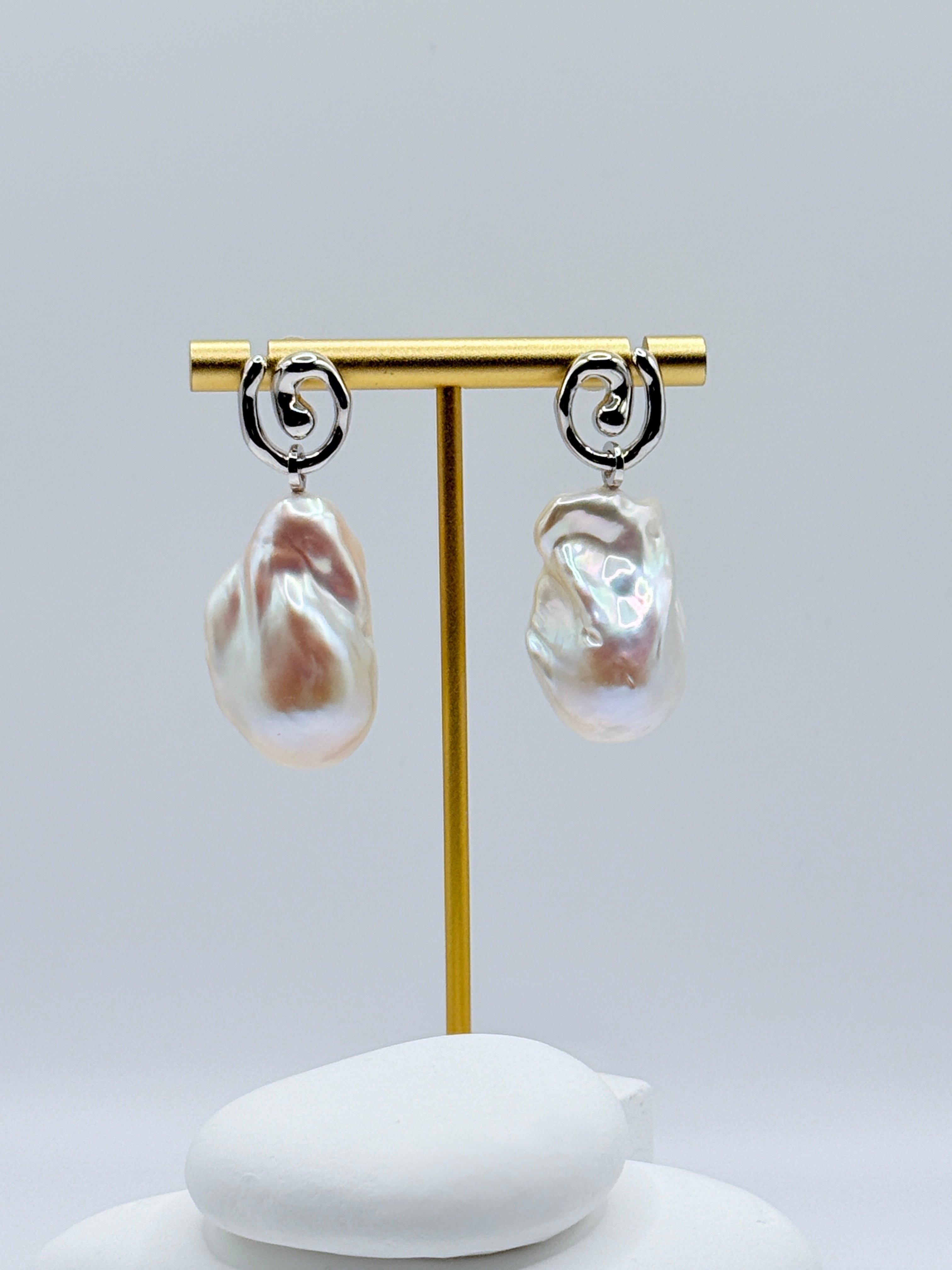 Close-up view of large baroque freshwater pearl earrings showing removable design and sterling silver curved accents on white stones
