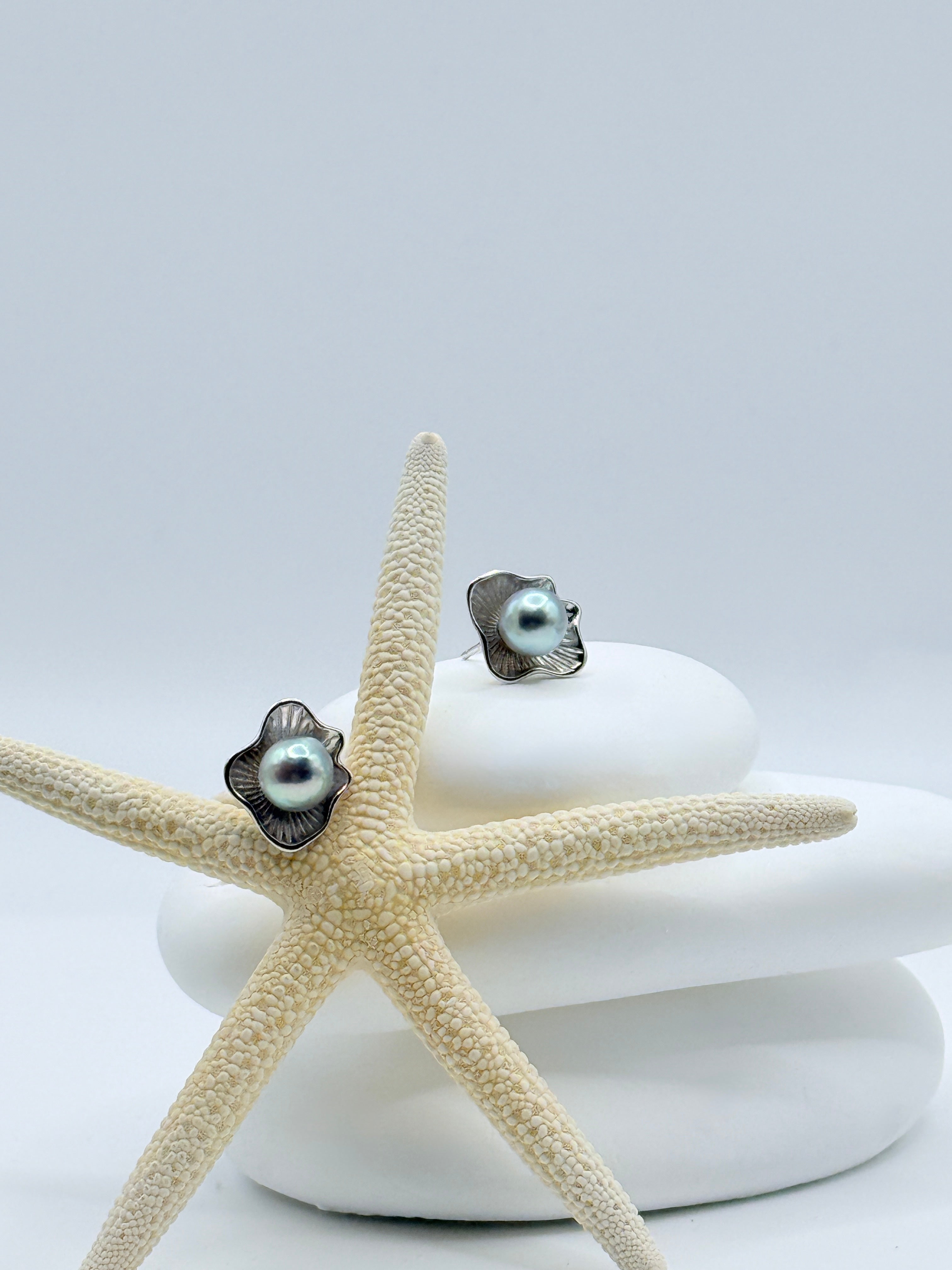 Close-up view of blue Akoya pearl studs in sterling silver petal settings showing azure lustre on white stones