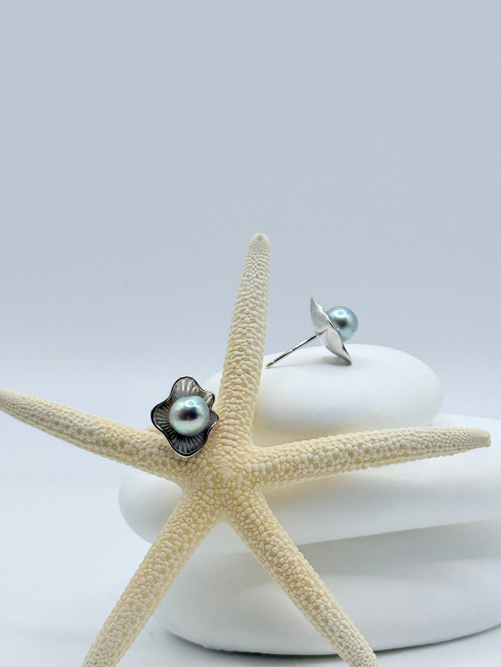Sterling silver flower petal ear studs with blue Akoya pearls displayed on starfish showing elegant floral design