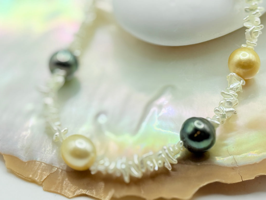 Close up of golden south sea pearl and green tahitian pearl on necklace with Southsea gold and Tahitian pearl on strand of akoya keshi on a golden oyster shell