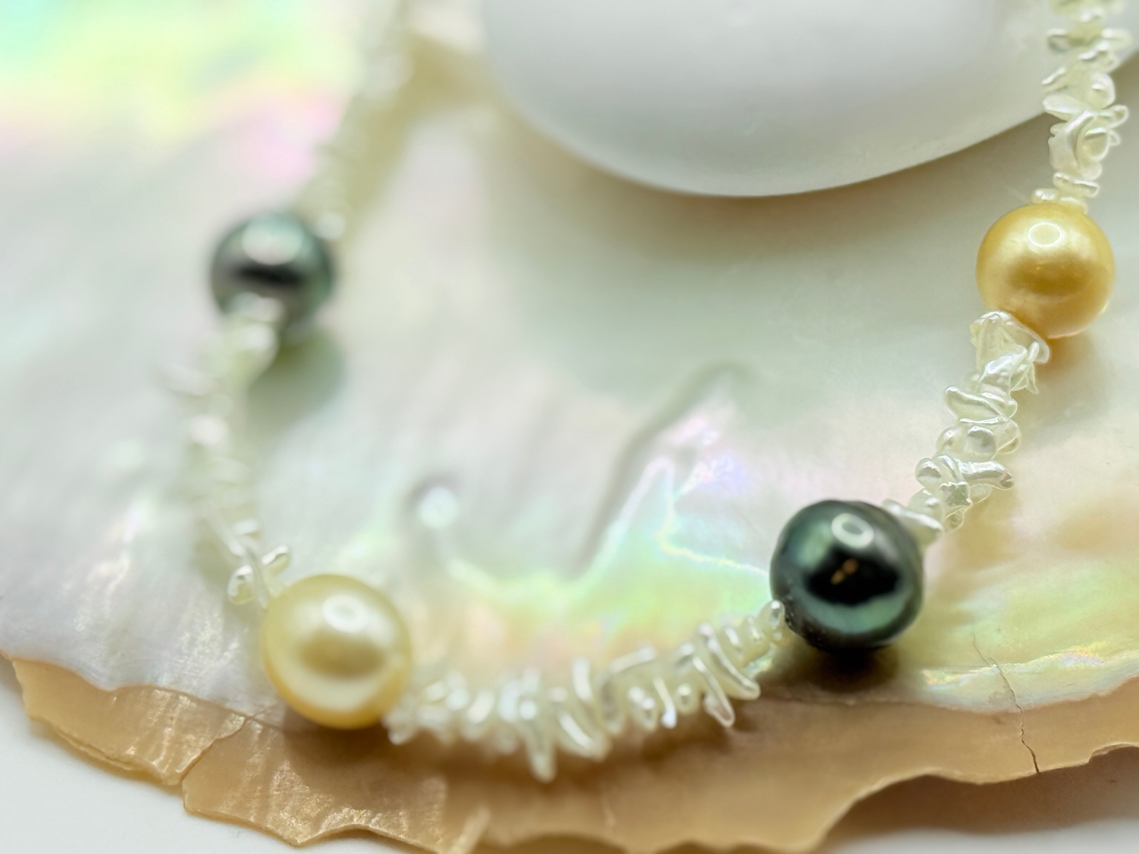 Close up of golden south sea pearl and green tahitian pearl on necklace with Southsea gold and Tahitian pearl on strand of akoya keshi on a golden oyster shell