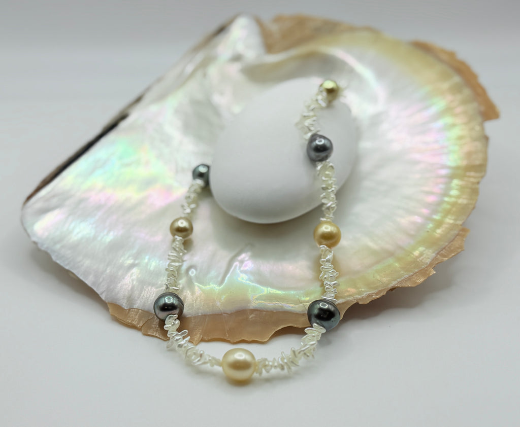 Side view of Pearl necklace with Southsea gold and Tahitian pearl on strand of akoya keshi on a golden oyster shell