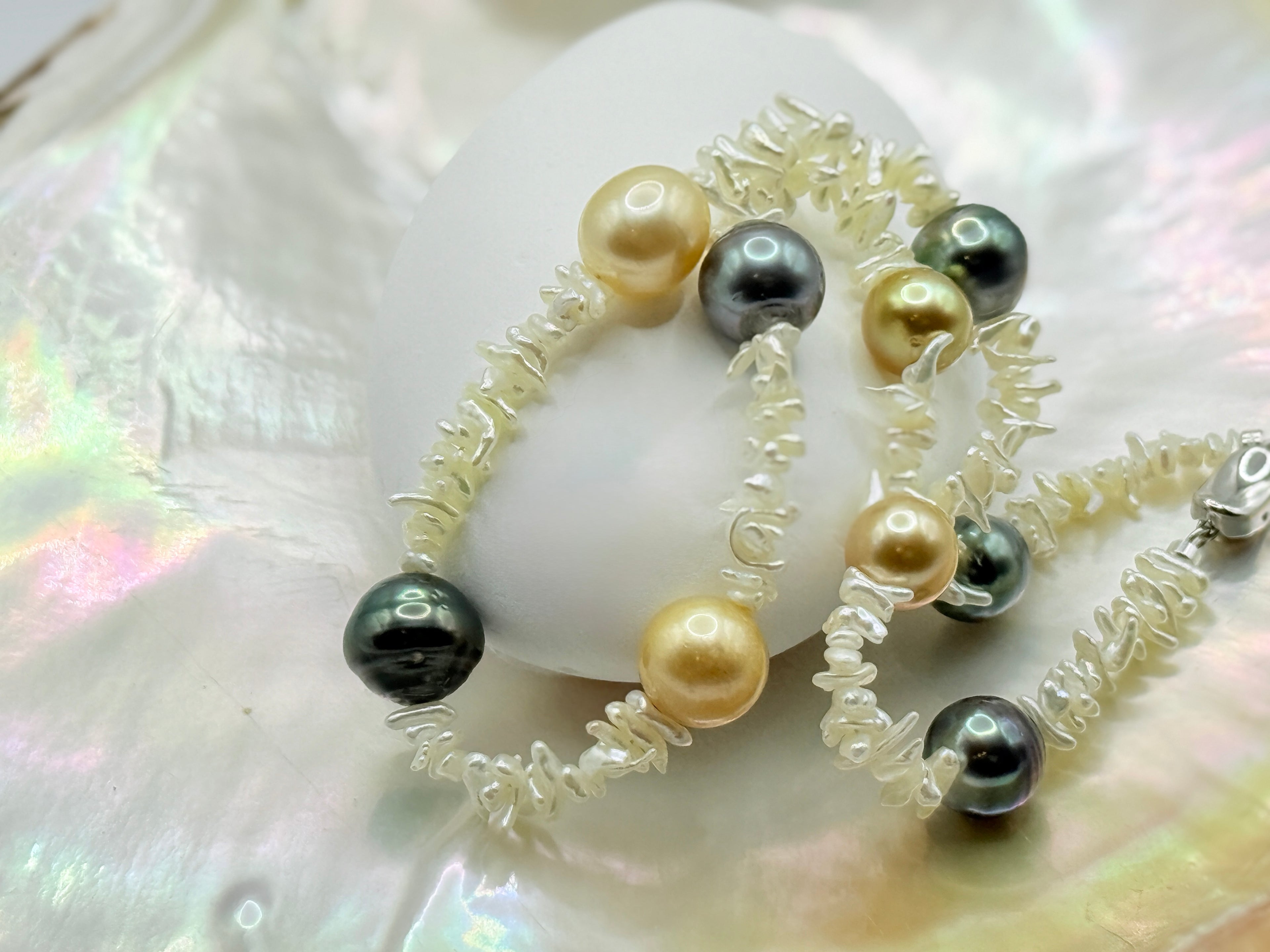 Close up view of Pearl necklace with Southsea gold and Tahitian pearl on strand of akoya keshi on a golden oyster shell