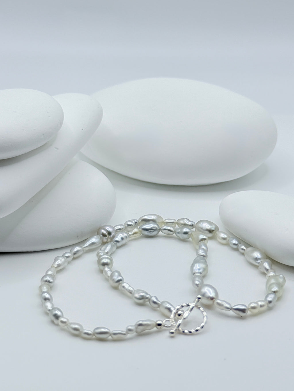 South Sea white keshi strand with sterling silver OT toggle clasp displayed on white stones showing varied organic shapes