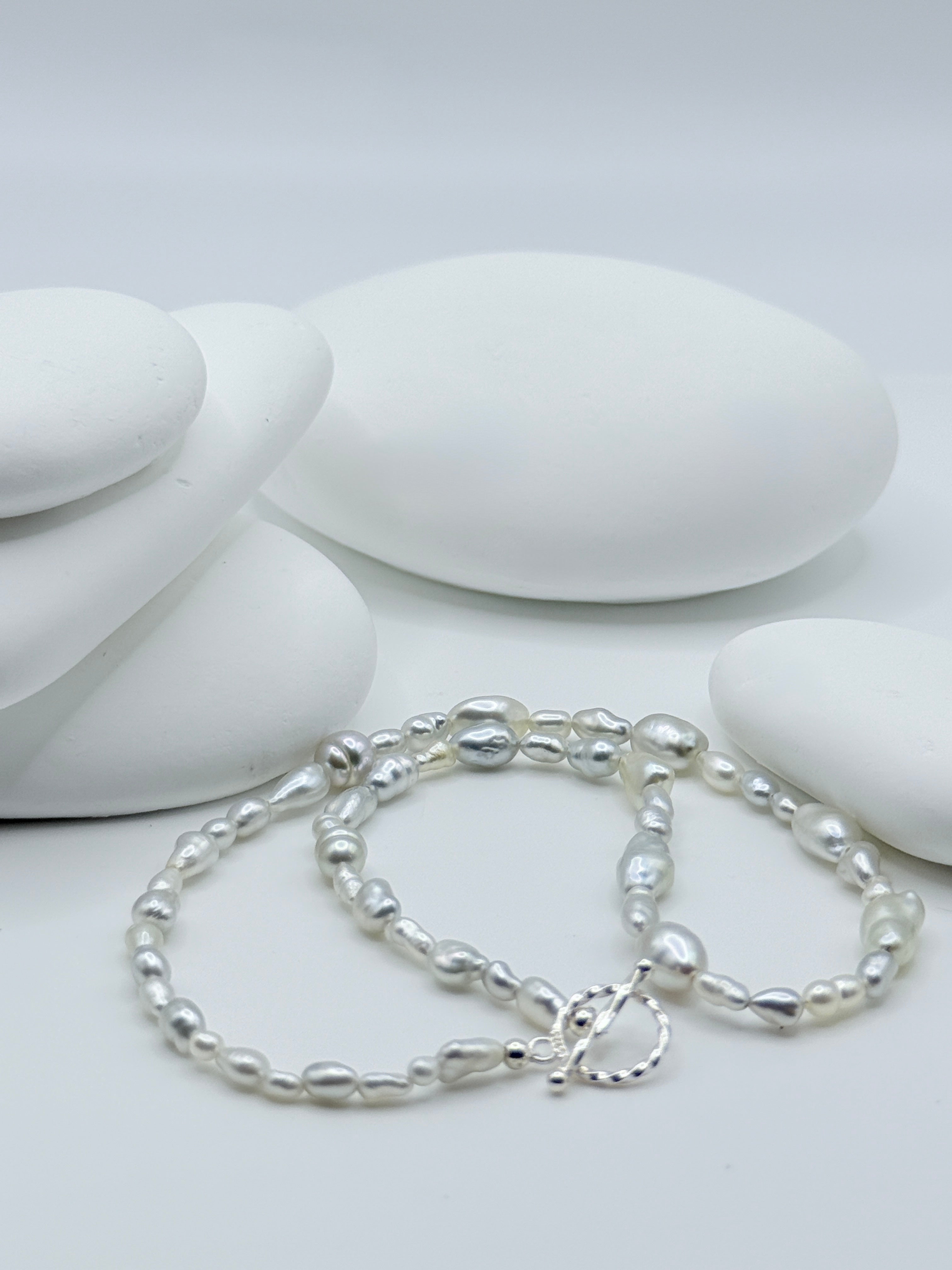South Sea white keshi strand with sterling silver OT toggle clasp displayed on white stones showing varied organic shapes
