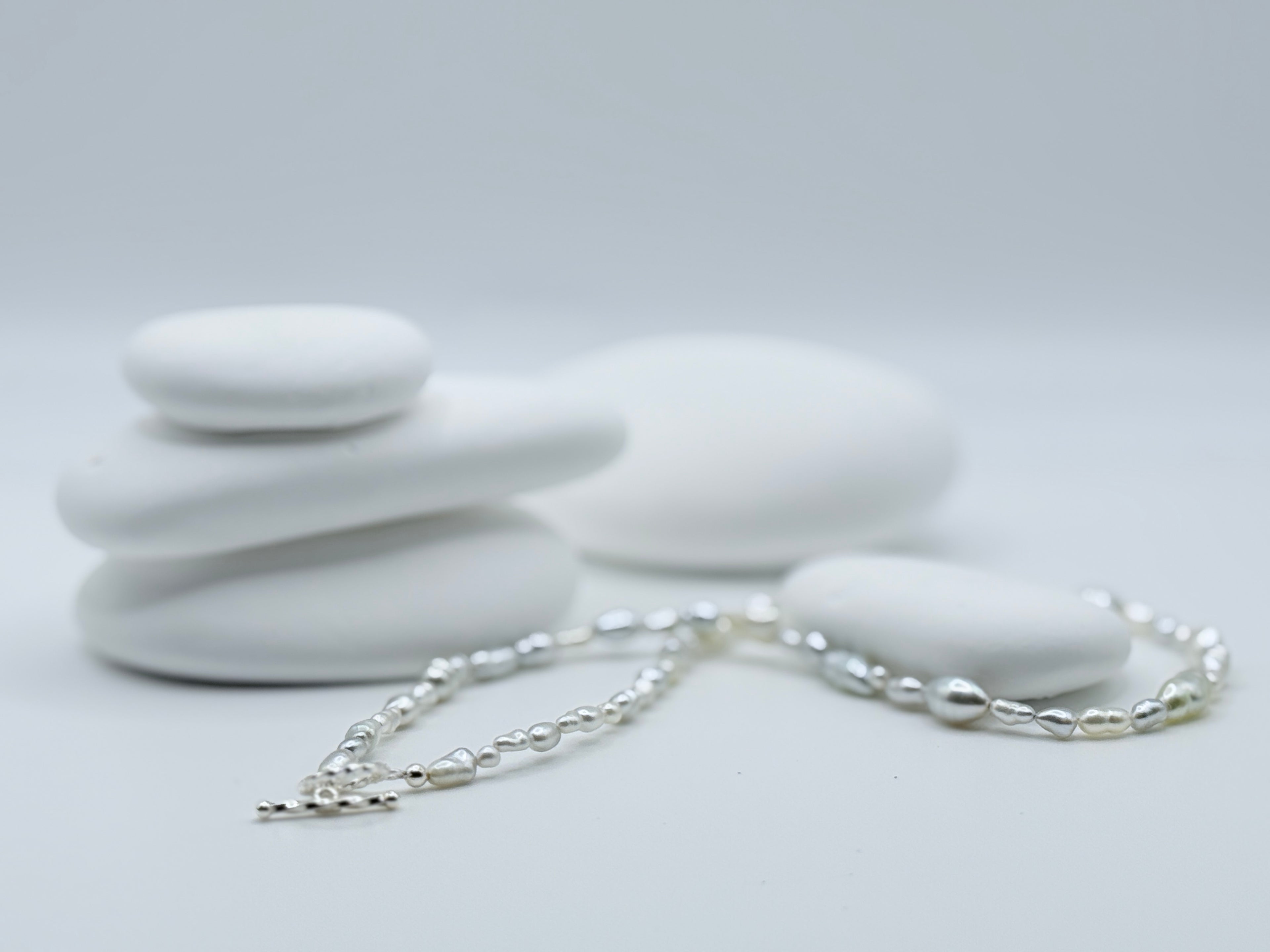 South Sea white keshi strand with varied shapes and sizes displayed on white stone arrangement highlighting natural beauty