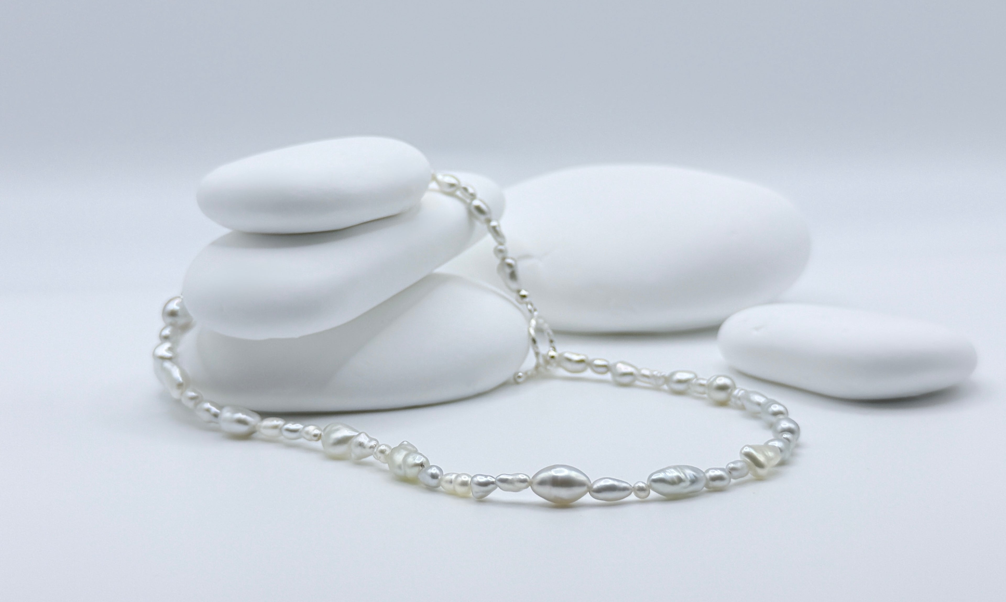 Close-up view of South Sea white keshi strand showing natural size variations and lustrous surfaces with silver toggle clasp