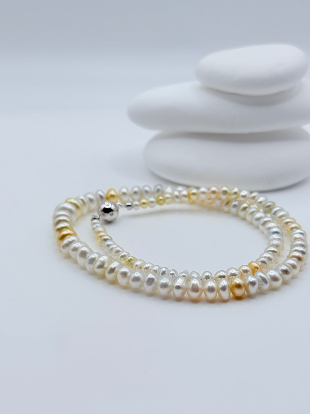 Close-up view of South Sea keshi roundel rivière strand displaying colour transition from gold to white with sterling silver clasp