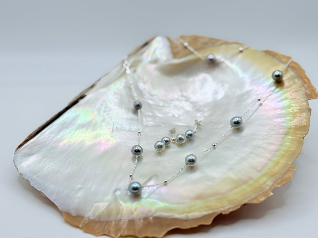Blue baroque Akoya pearl station necklace and drop earrings set in sterling silver displayed on white shell