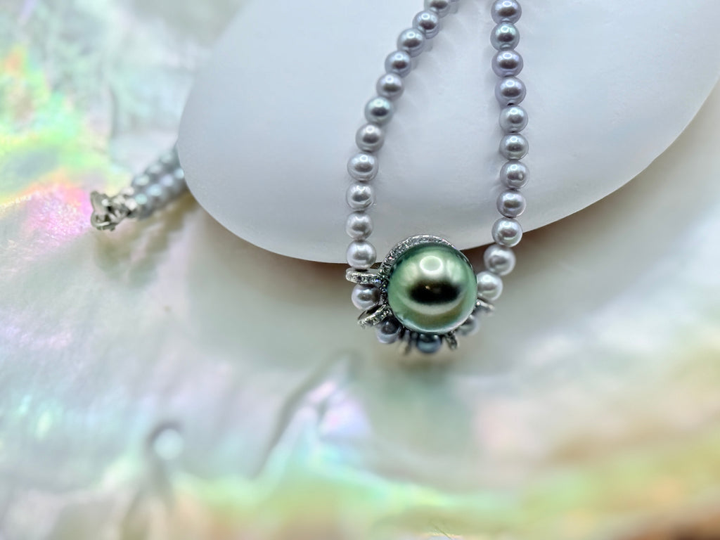 Close-up of 11mm green Tahitian pearl pendant with grey 3.5mm seed pearl strand on mother of pearl shell