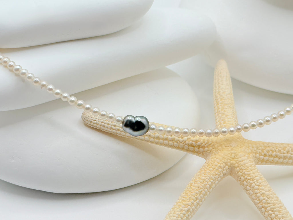 Close-up detail of heart-shaped Tahitian keshi pendant on 2.5mm white freshwater seed pearl strand