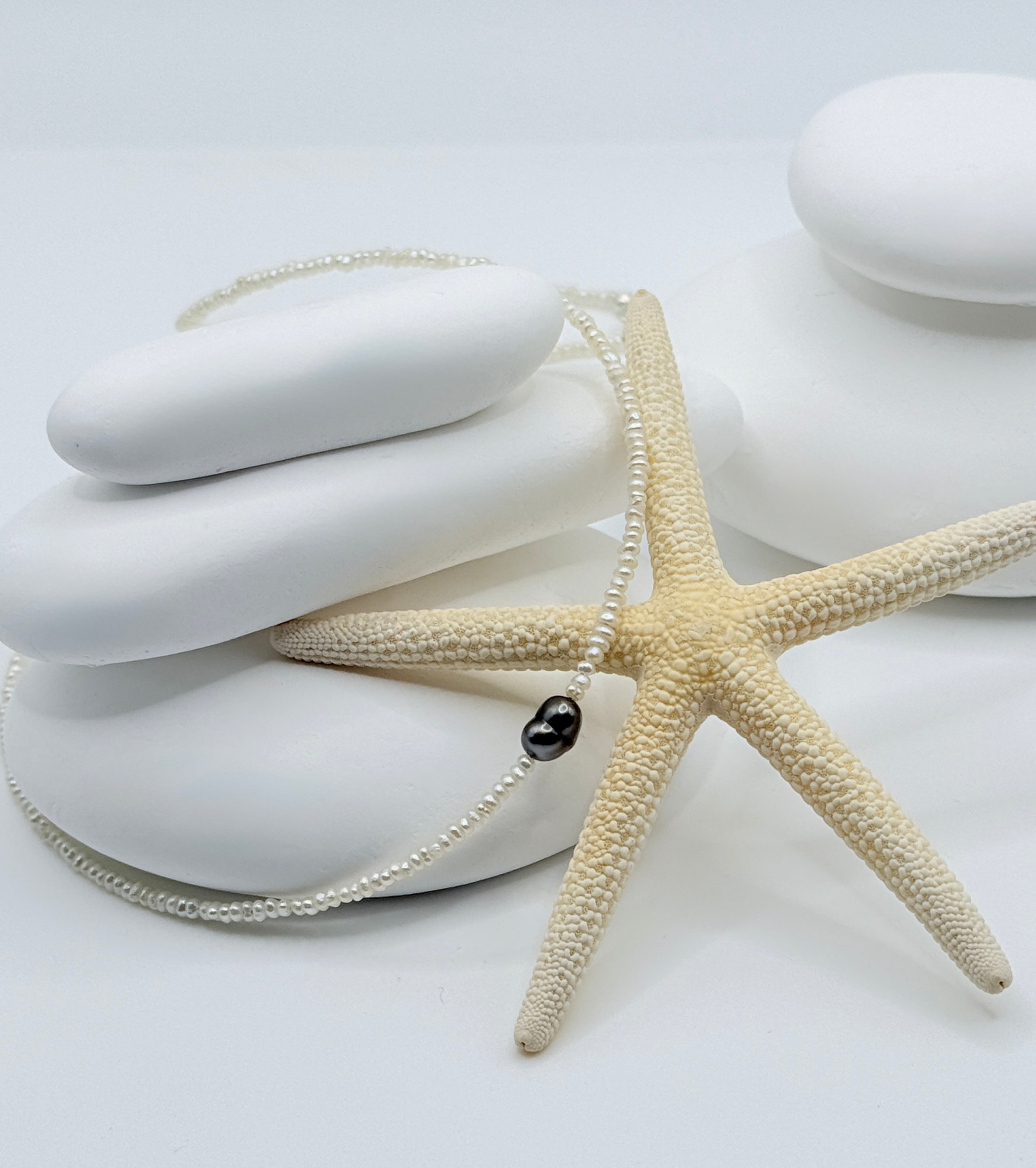 White seed pearl choker necklace featuring heart-shaped Tahitian keshi pendant on white shells