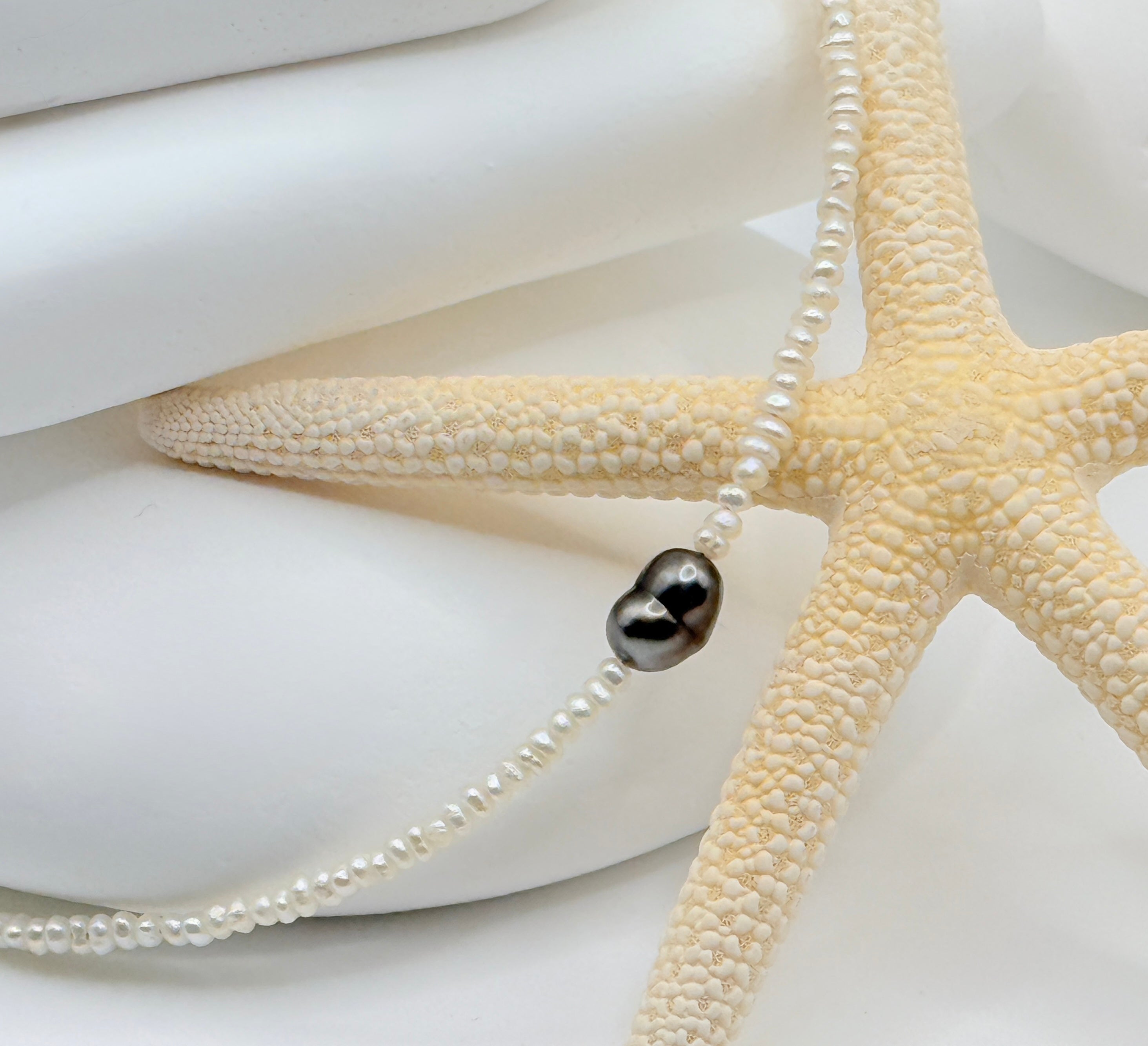 Close-up detail of heart-shaped Tahitian keshi pendant on white freshwater seed pearl strand