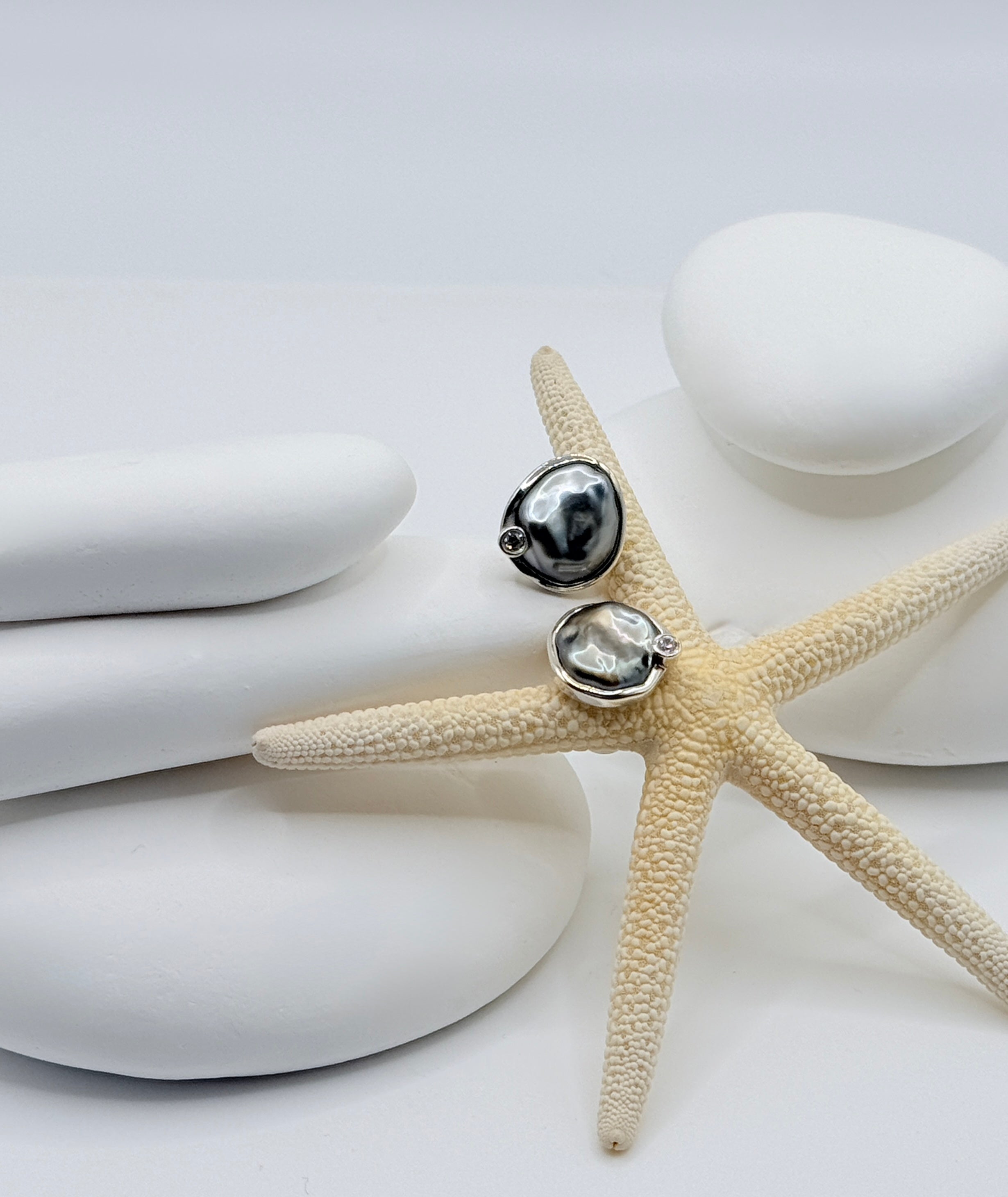 Close-up of 10-12mm Tahitian keshi pearl studs with single moissanite accent in sterling silver close-back setting